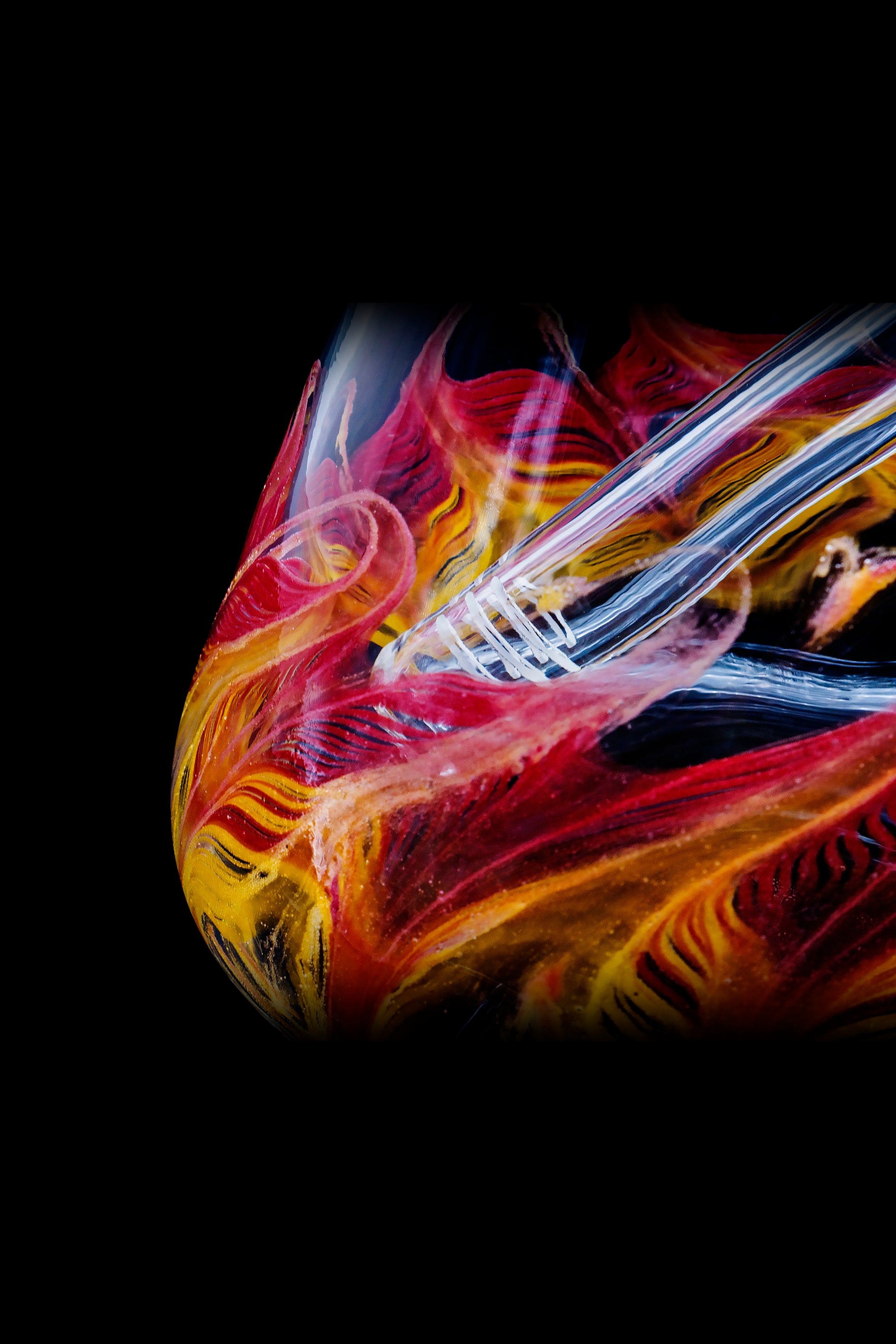 Vibrant glass pipe with swirling red, orange, and yellow patterns against a black background.