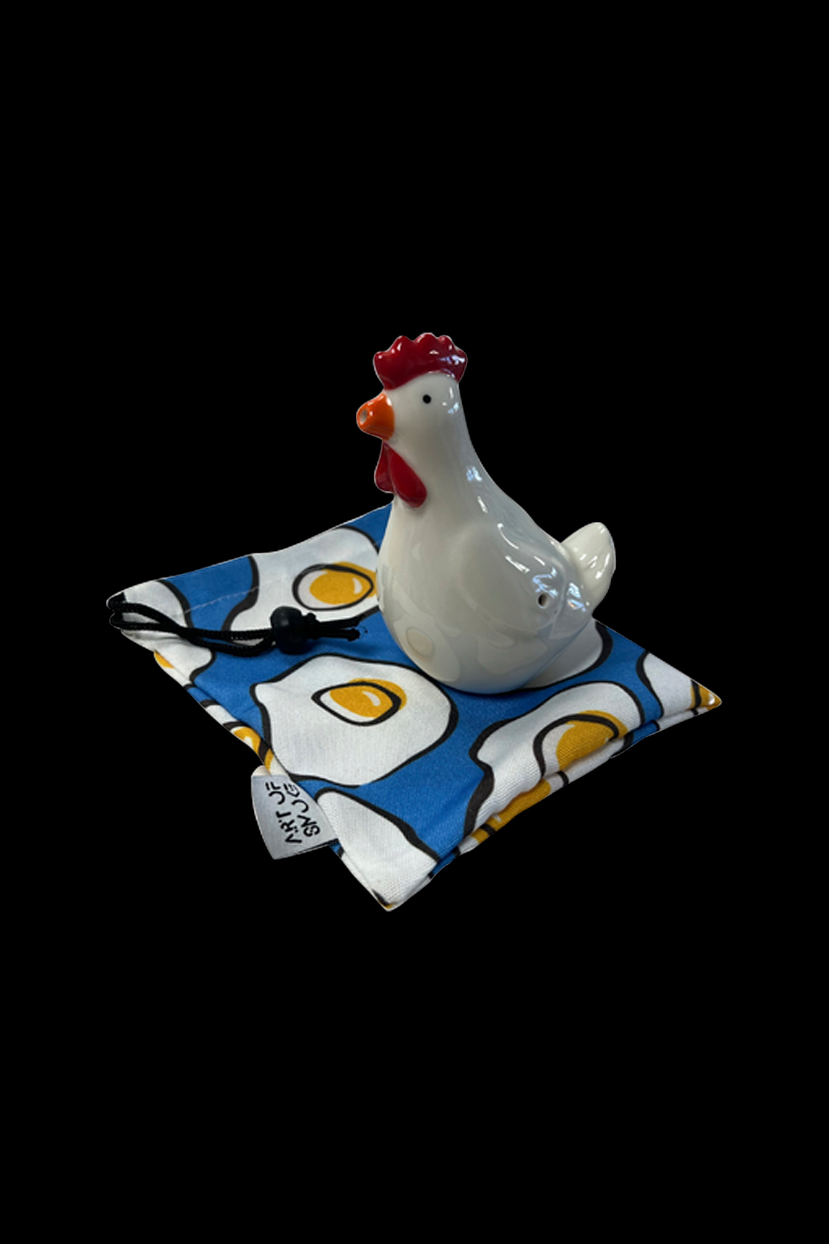 Ceramic chicken figurine resting on a patterned cloth resembling fried eggs, likely a themed accessory for cannabis use.