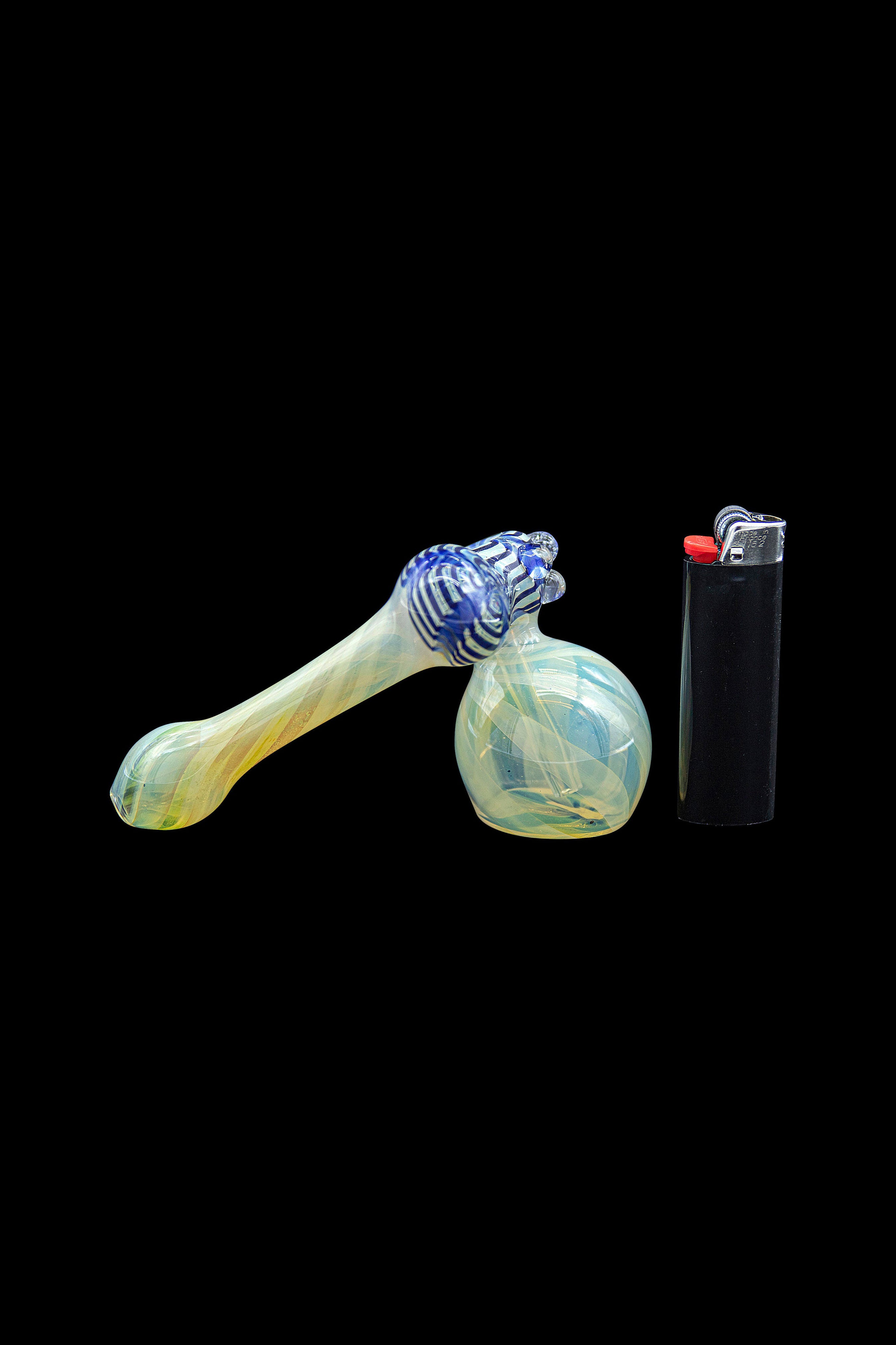 Glass pipe with blue and yellow swirls next to a black lighter on a black background.