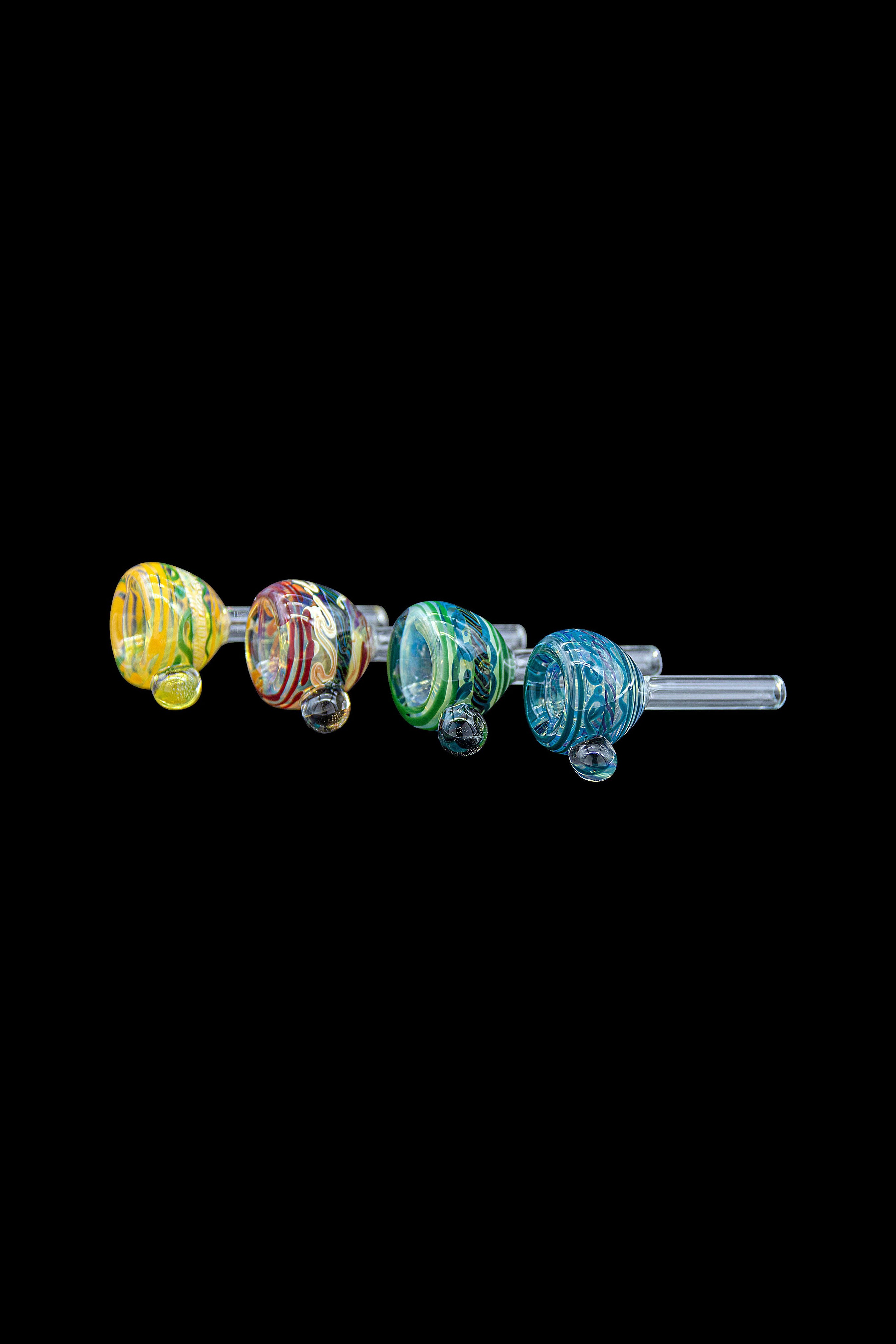 Assorted colorful glass cannabis oil burners displayed in a row on a black background.