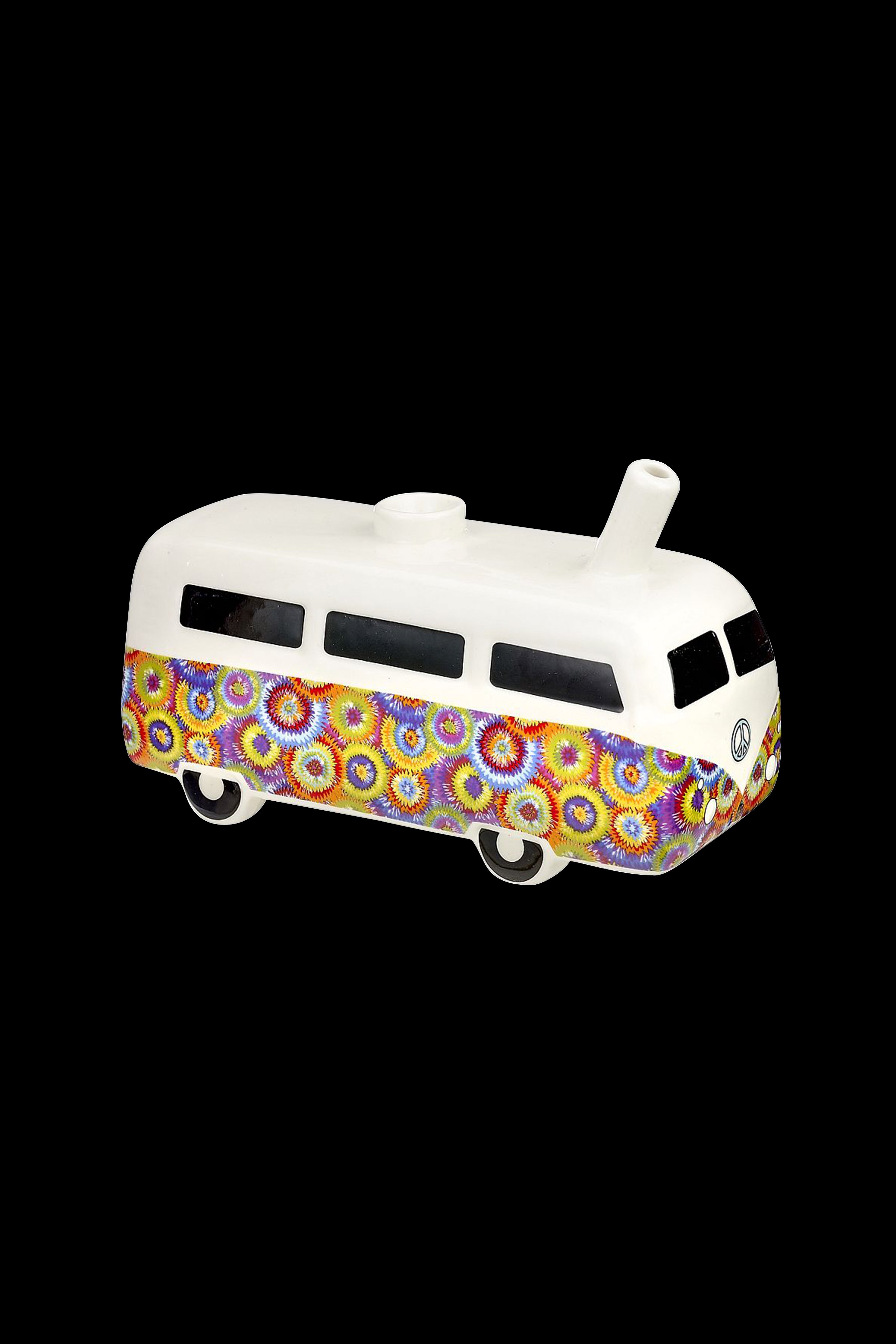 White ceramic VW bus-shaped water pipe with colorful psychedelic floral patterns, isolated on a black background.