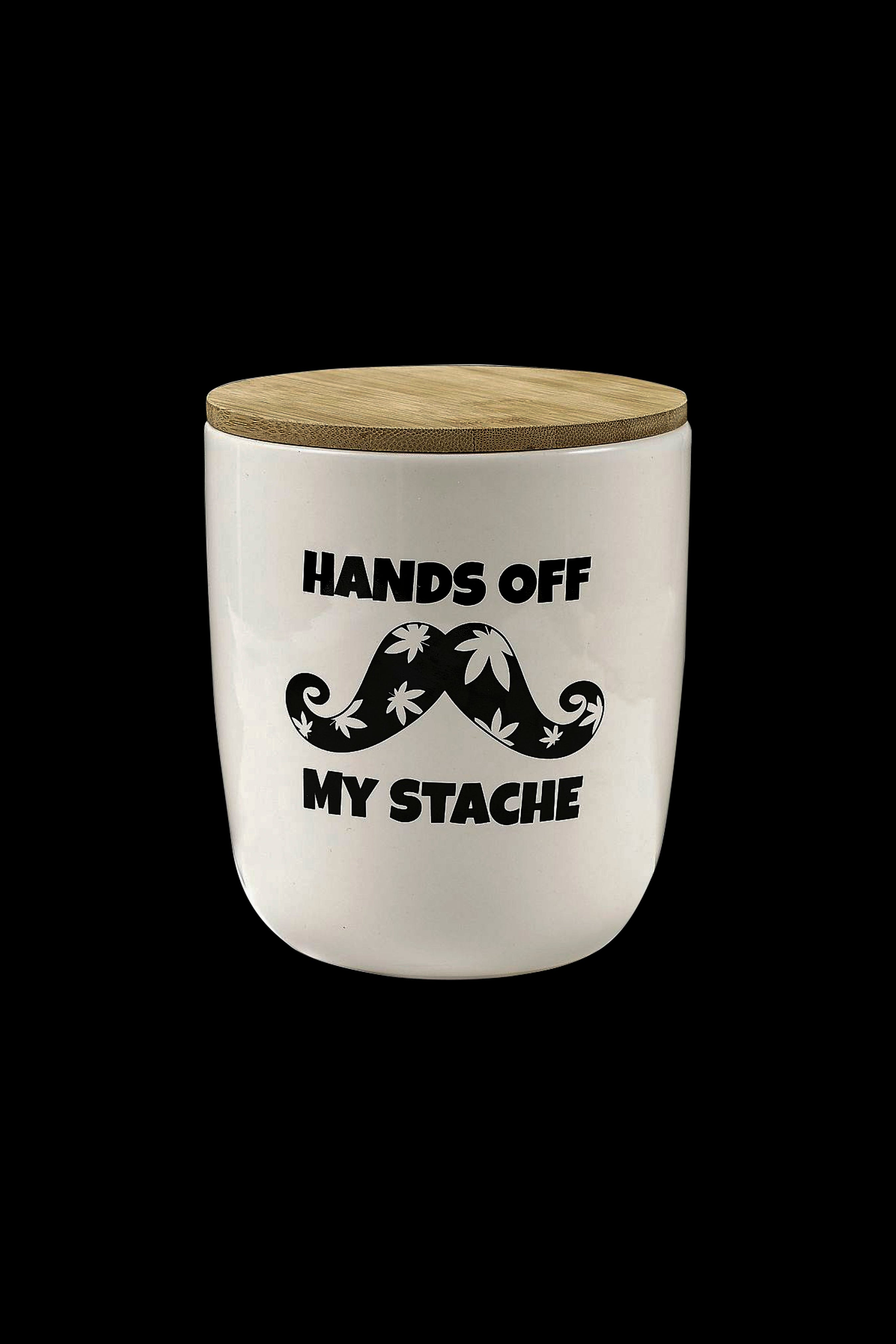 White storage container with a bamboo lid, featuring a black mustache decorated with cannabis leaves and the text "HANDS OFF MY STACHE".
