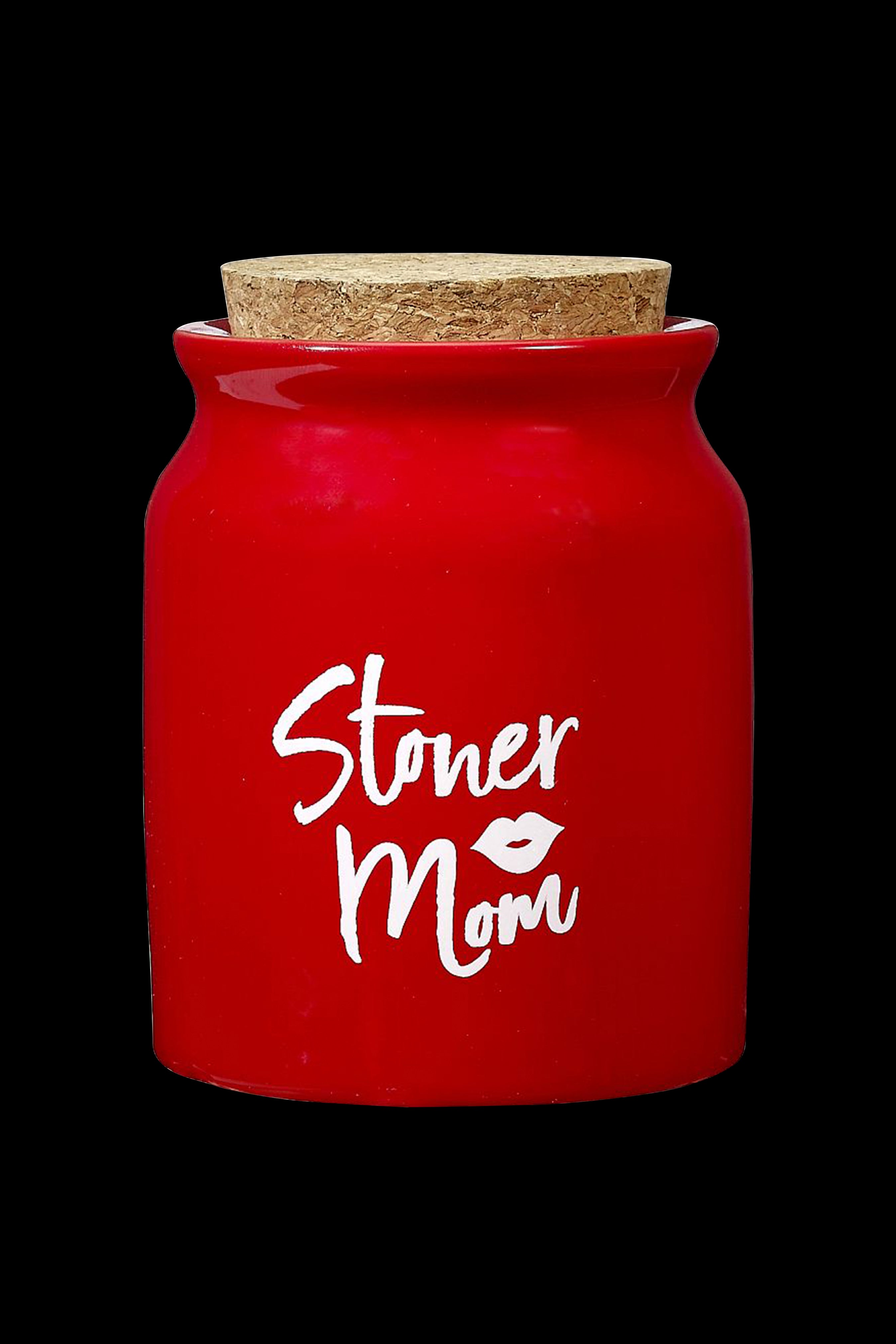 Red ceramic jar with a cork lid, featuring white script reading "Stoner Mom" with a leaf detail.