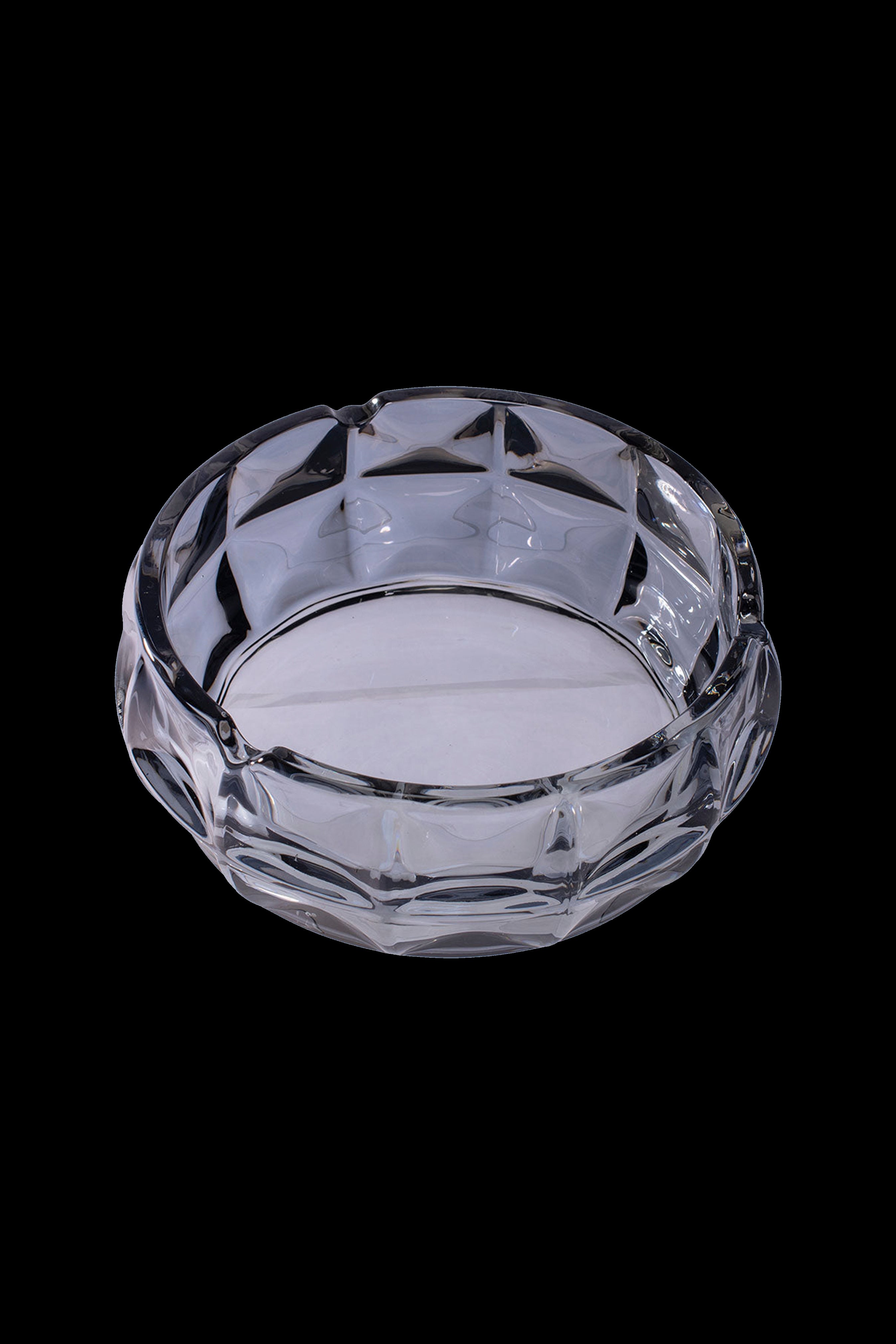 Clear glass ashtray with a geometric faceted design, isolated on a black background.