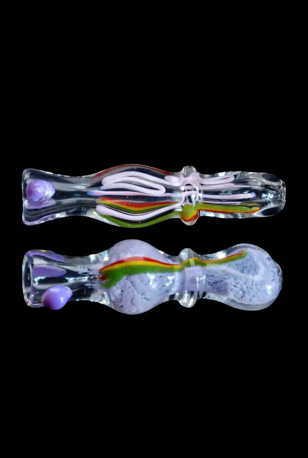 Top-down view of two clear glass Smoke Cartel Frit Rasta One Hitter - 3 in. pieces with internal rainbow and purple frit accents against a black background