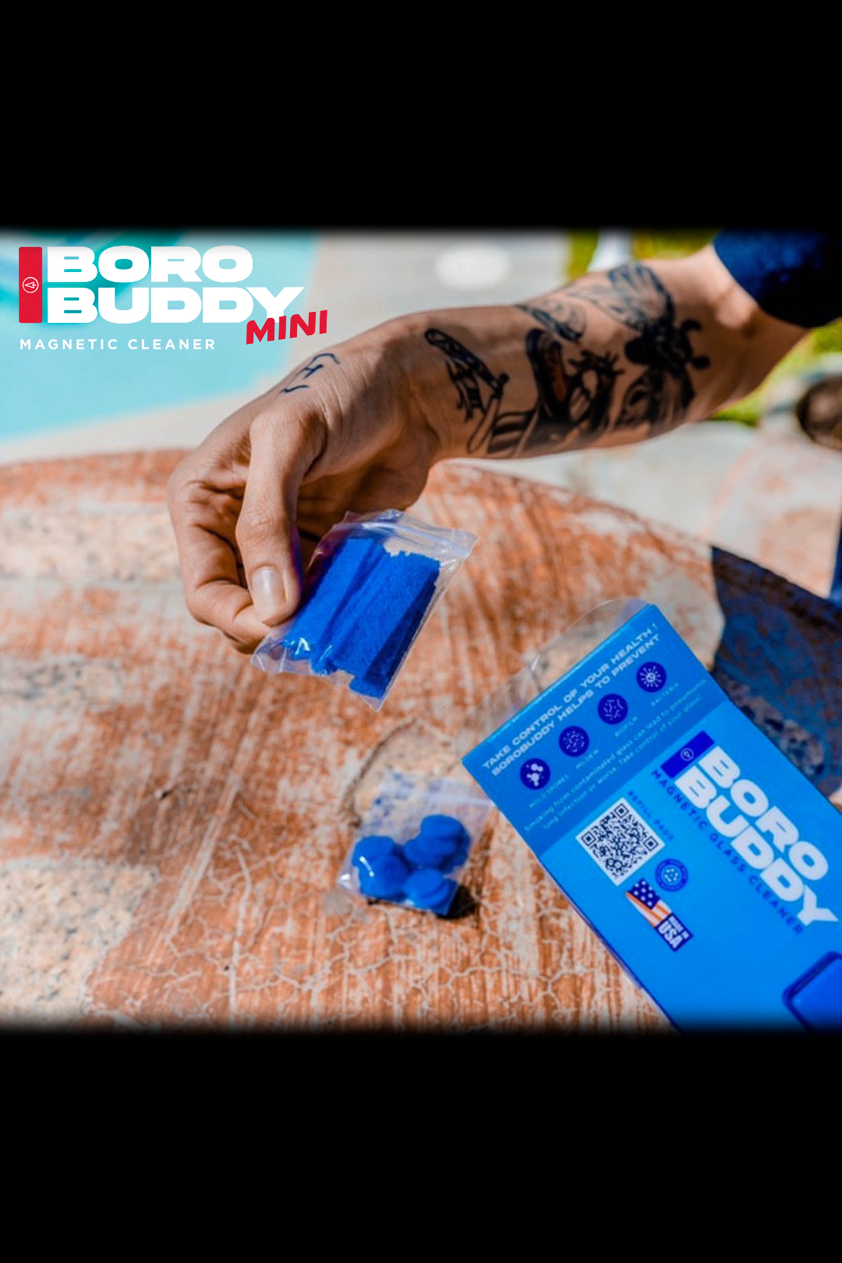 Close-up of a hand cleaning a glass pipe with a blue magnetic cleaner, product packaging visible in the background.