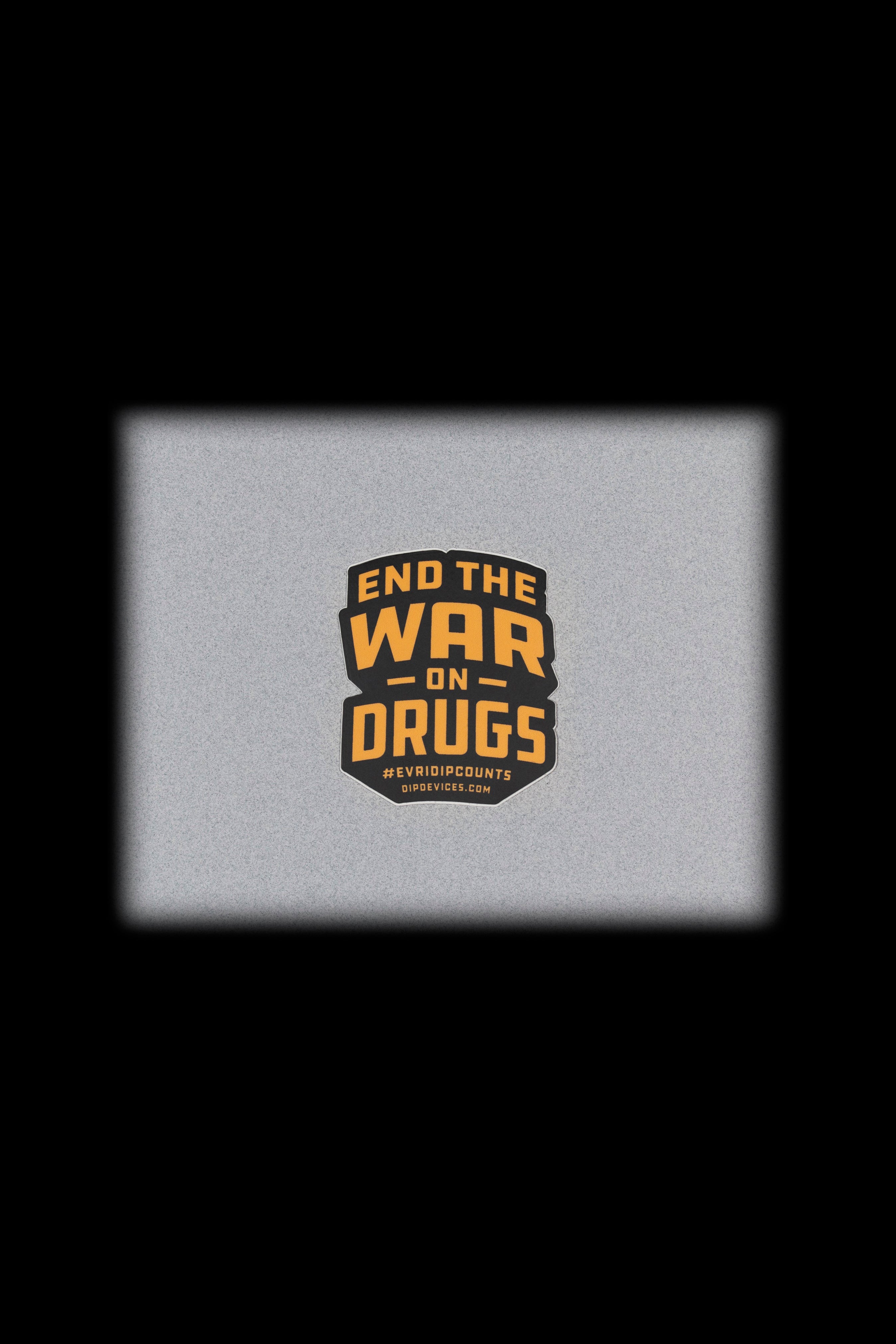 A square, textured gray background displays a circular badge with the text "END THE WAR ON DRUGS" and "#EVDIPCOUNTS" with a website address below.