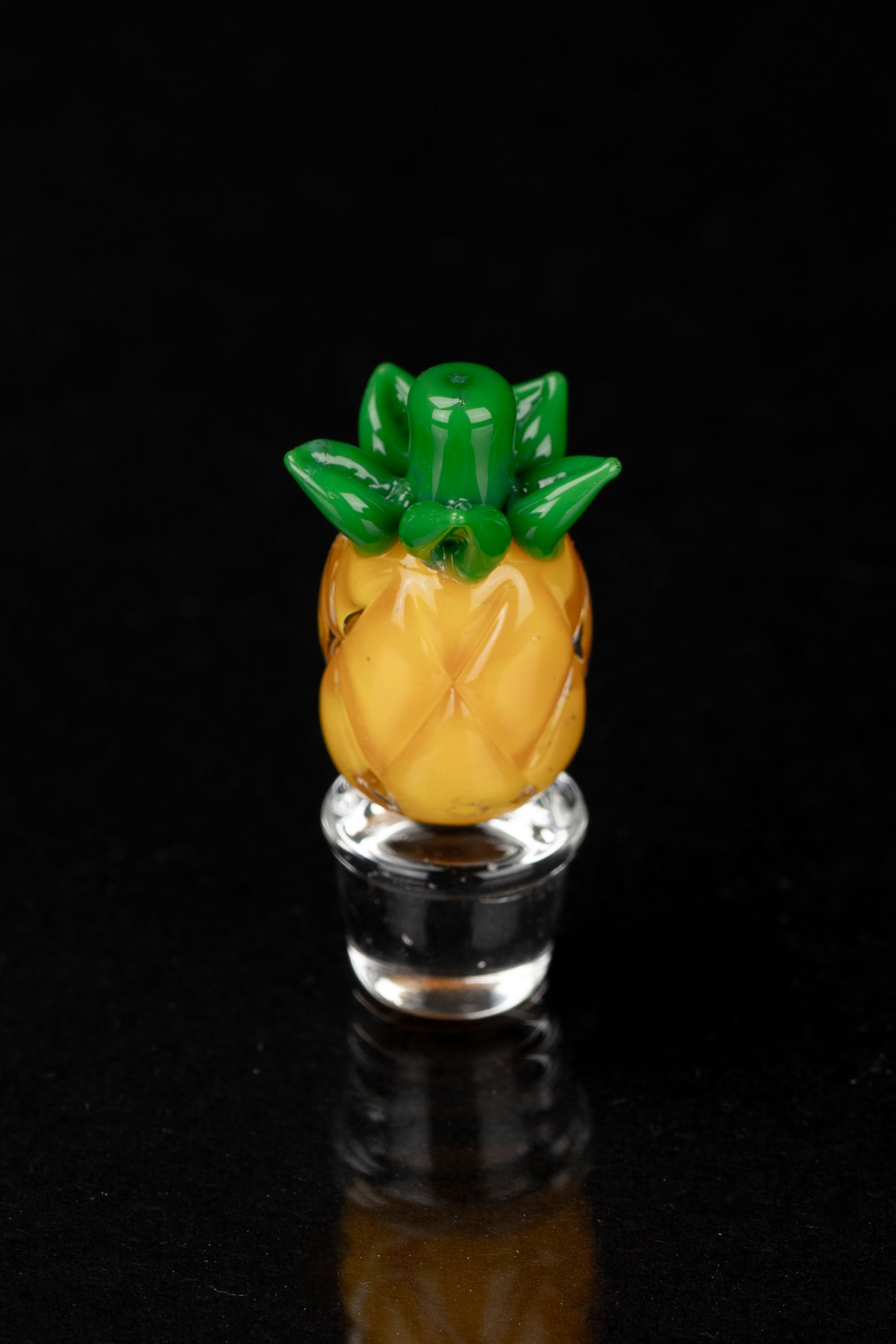 Glass pineapple-shaped oil rig bubbler against a black background.