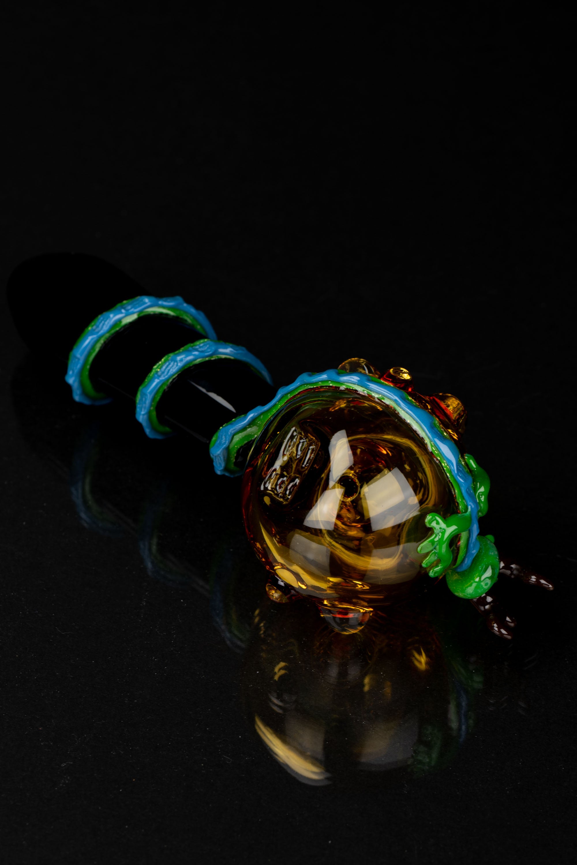 Glass cannabis pipe with colorful swirls against a black background.