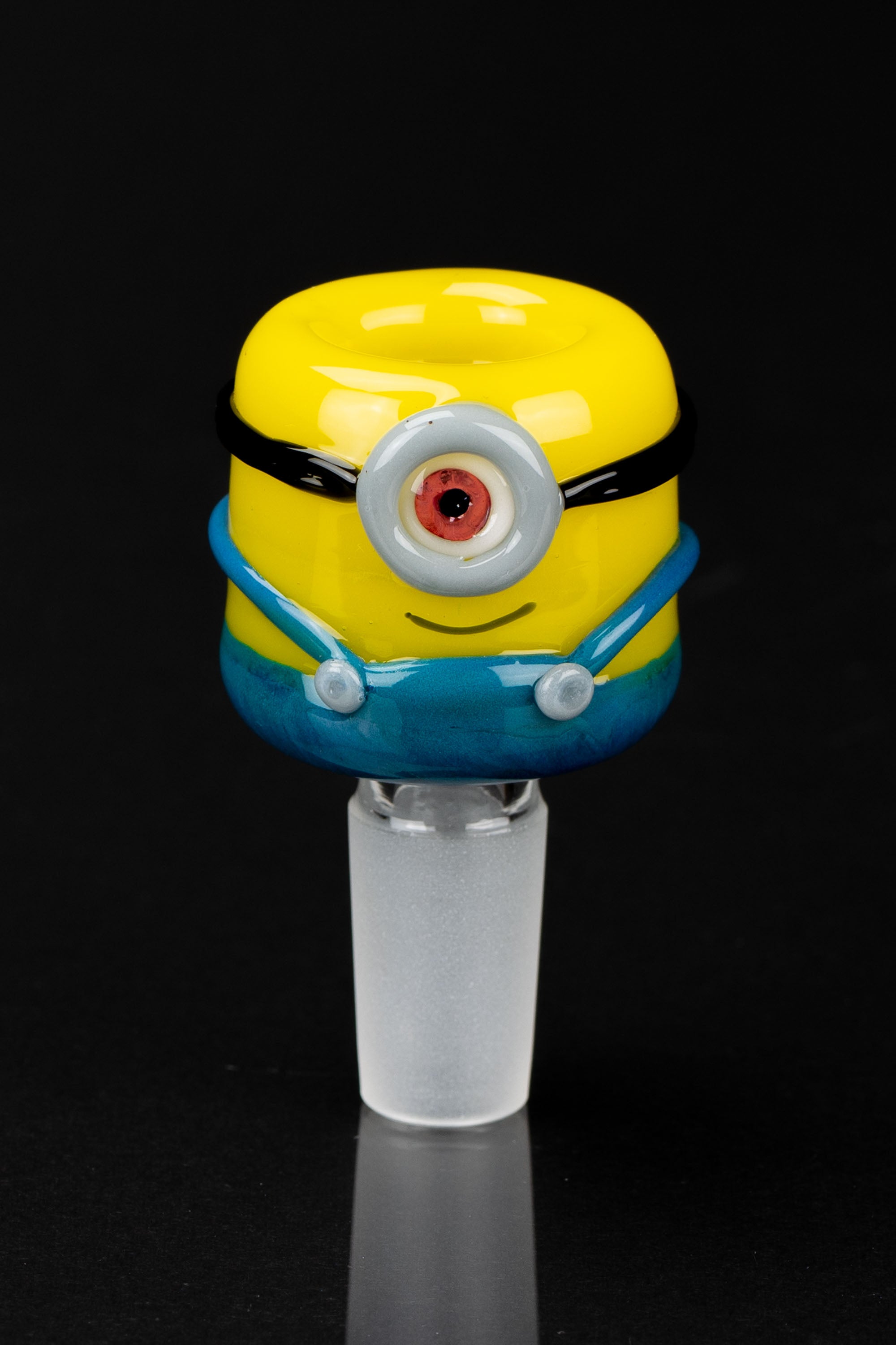 A glass bong bowl shaped like a Minion character, featuring a yellow head, blue overalls, and one large eye.