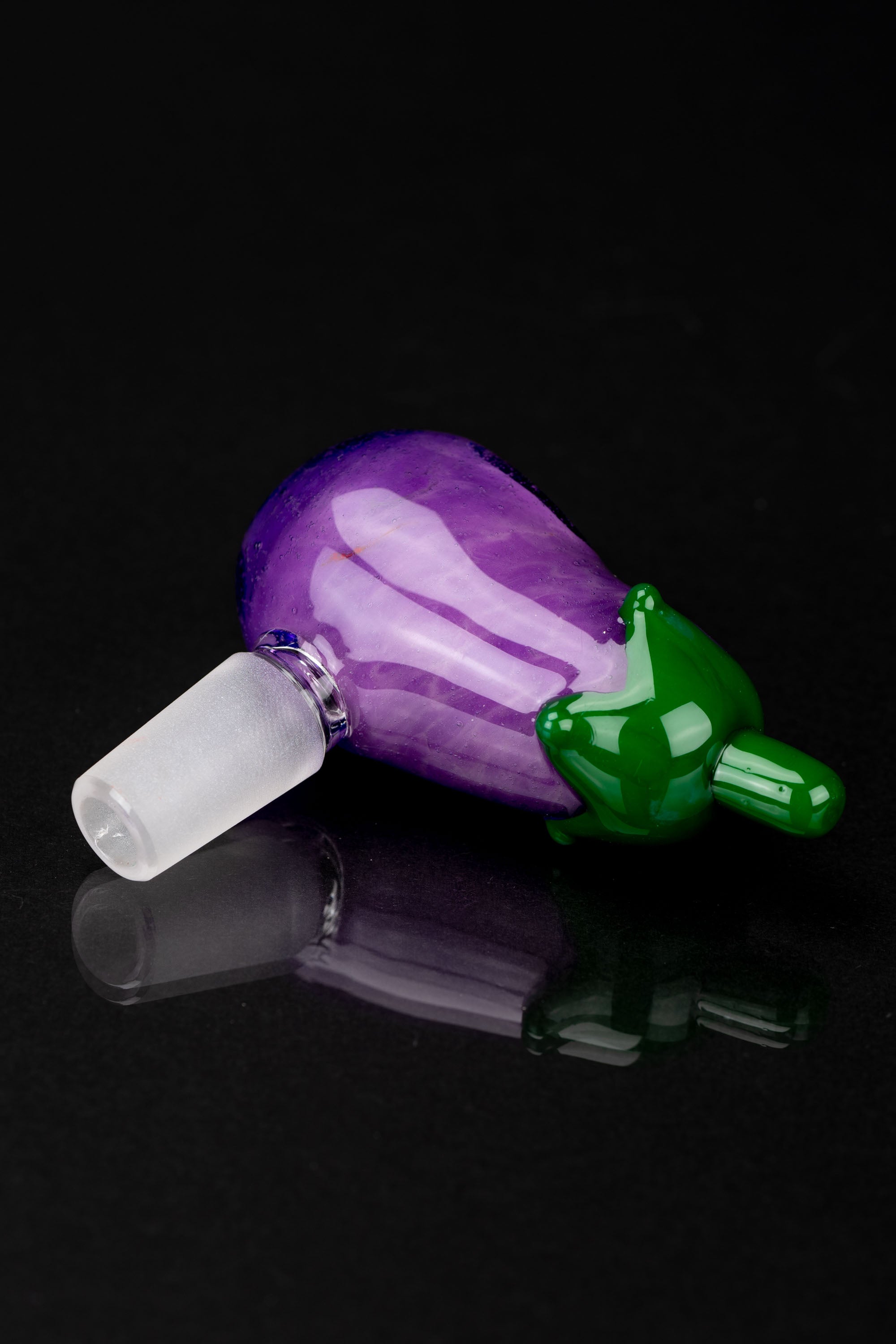 Purple and green glass cannabis water pipe attachment on a reflective surface.