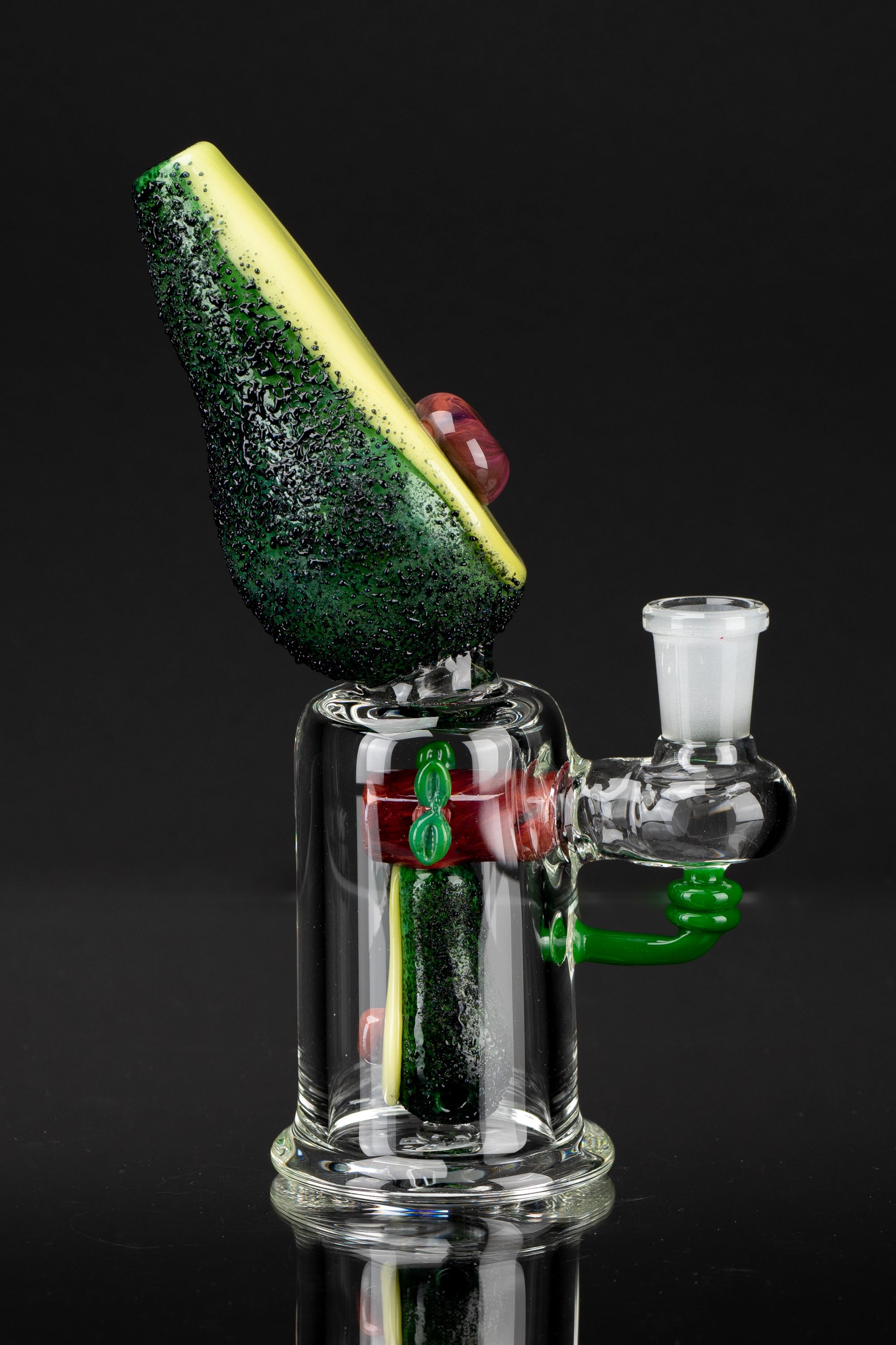 Hand-blown glass water pipe with avocado-themed details, studio shot.