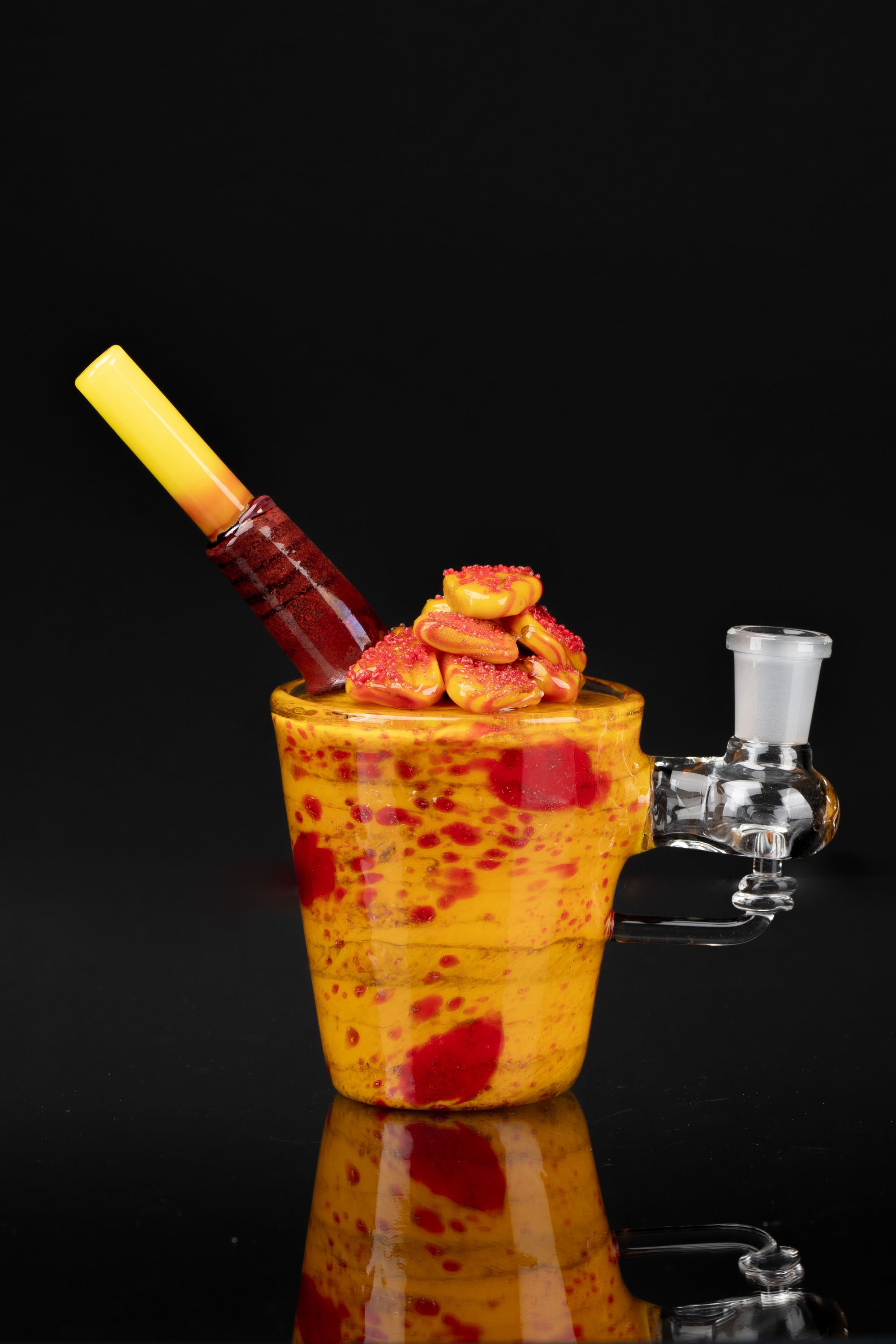 A vibrant, speckled glass bubbler with a loaded bowl of cannabis buds, against a black background.