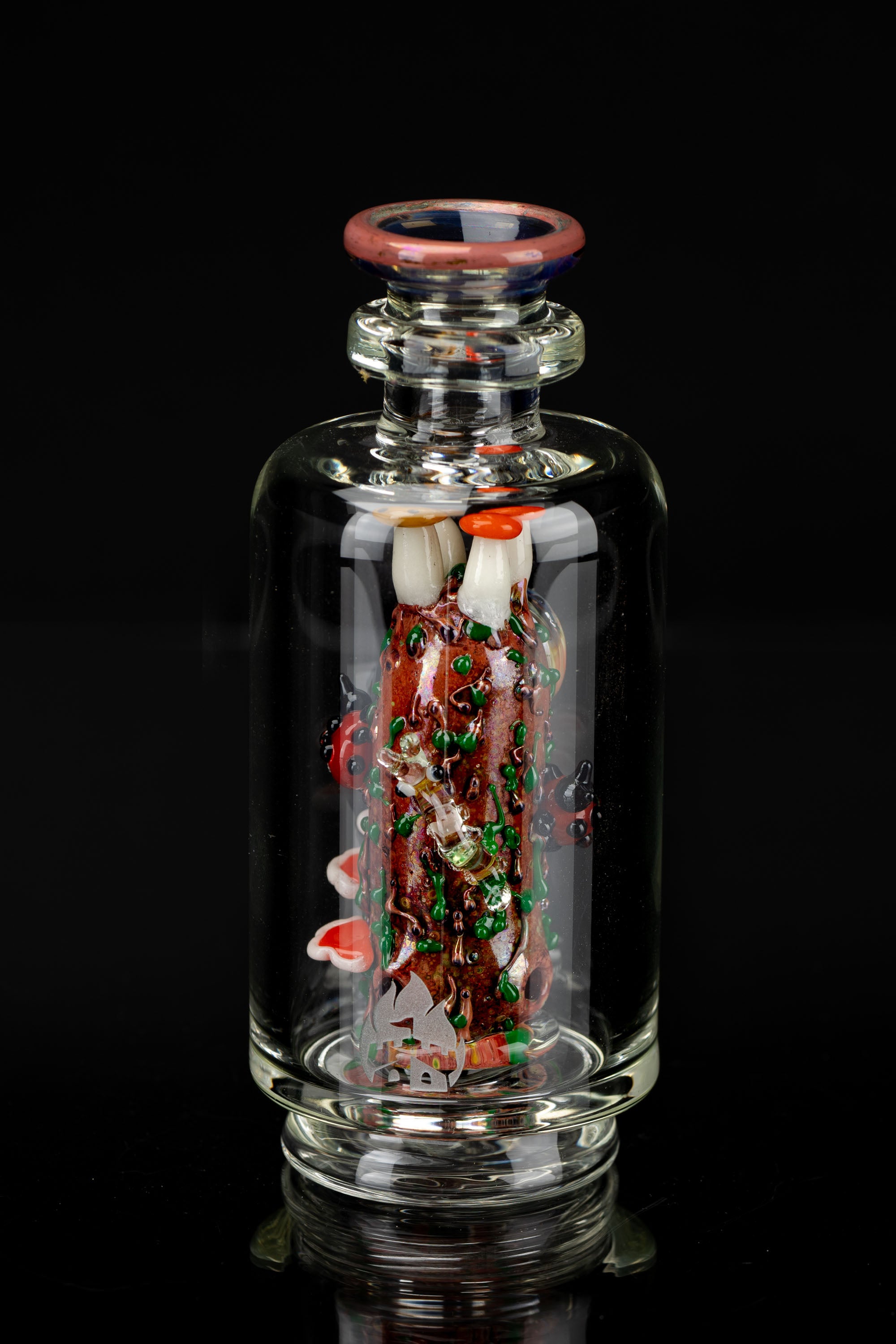 A vibrant, hand-blown glass bubbler featuring intricate red and green glasswork resembling a festive, whimsical forest scene within a clear glass body.
