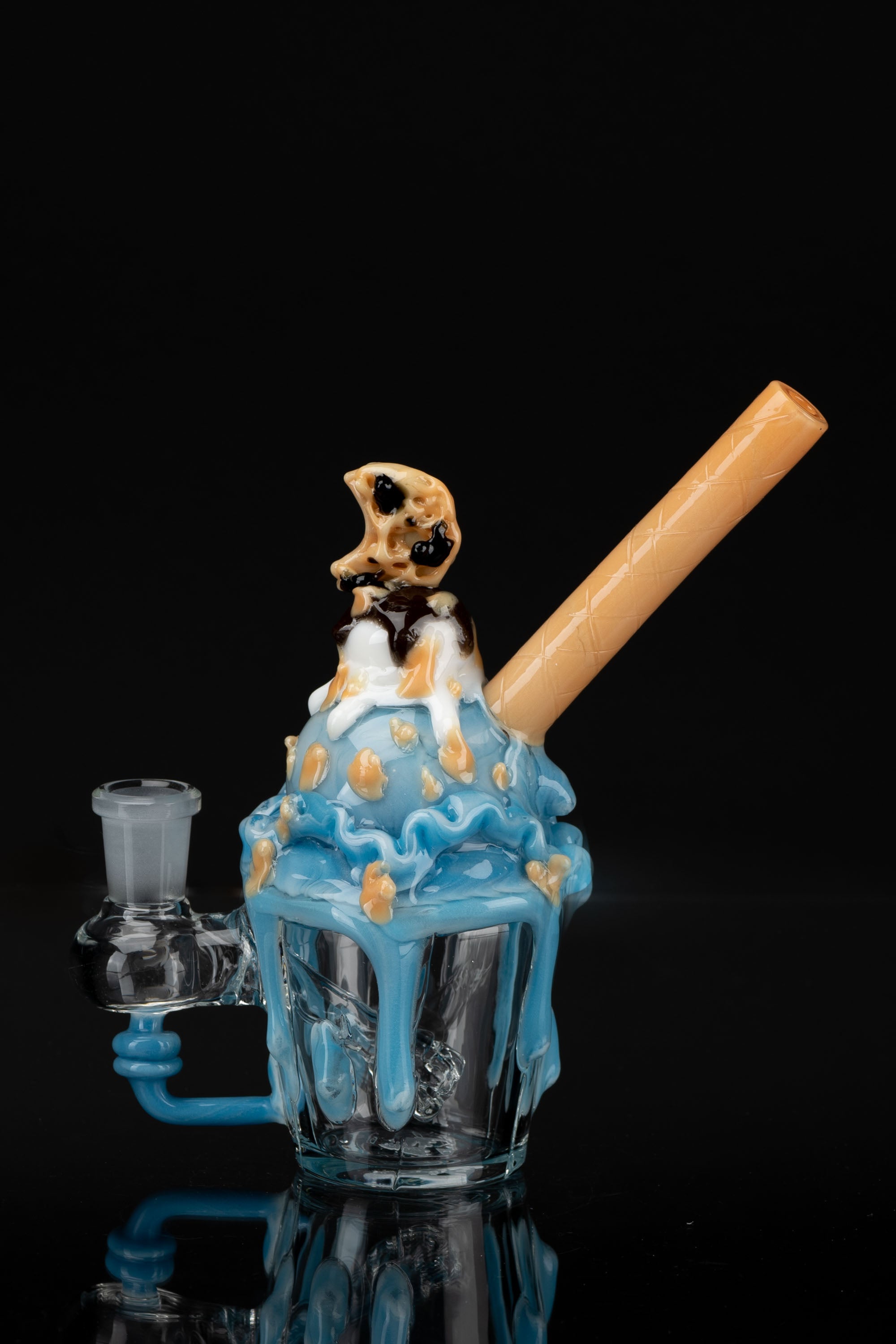 A sculpted glass water pipe resembling a blue ice cream sundae with chocolate and caramel drizzle, topped with a sculpted pretzel and a curved mouthpiece.