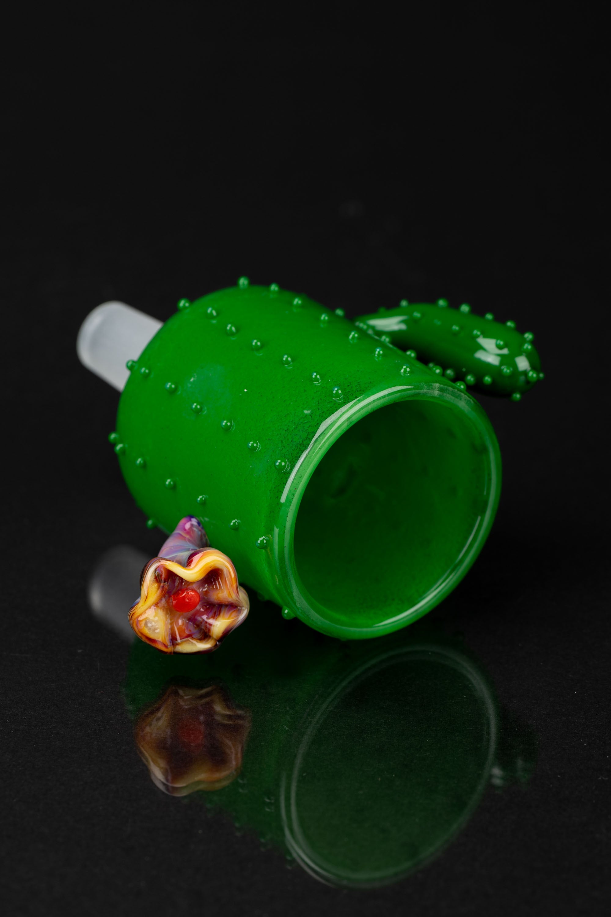 Green glass cactus-shaped bubbler with a colorful glass mouthpiece, isolated on a black background.