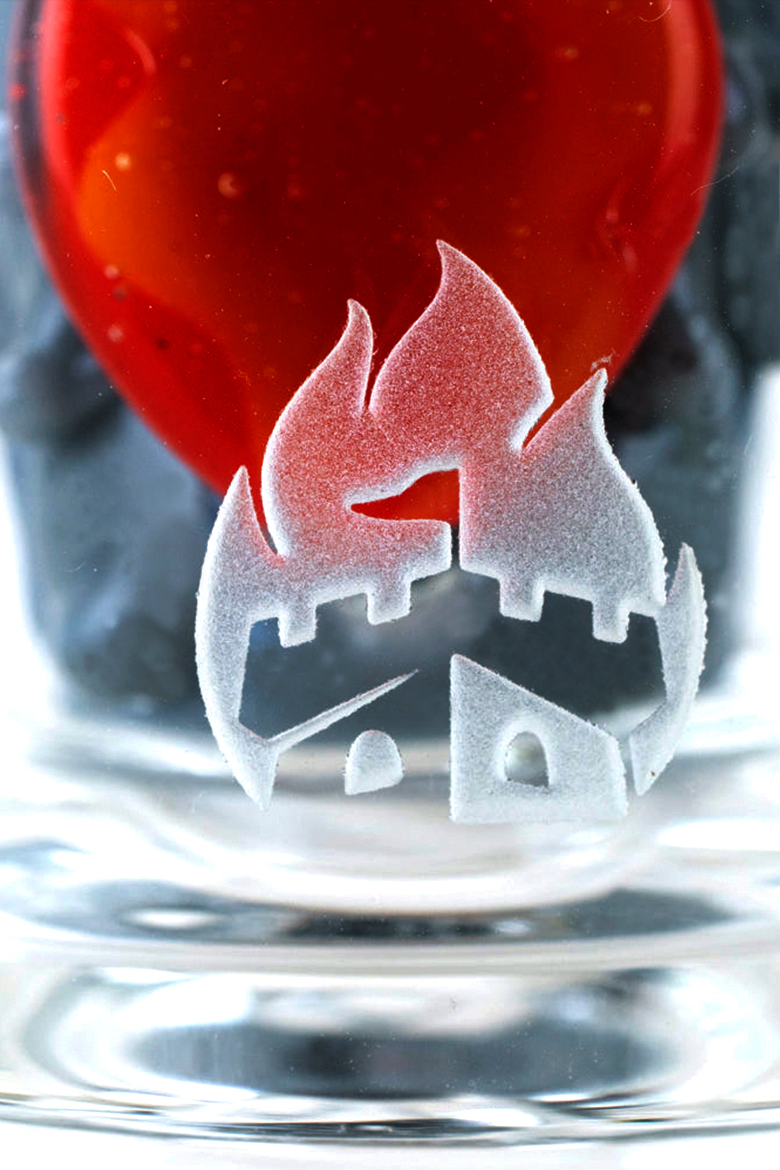 Frosted cannabis leaf design on a glass pipe submerged in water, with a red cap visible above.