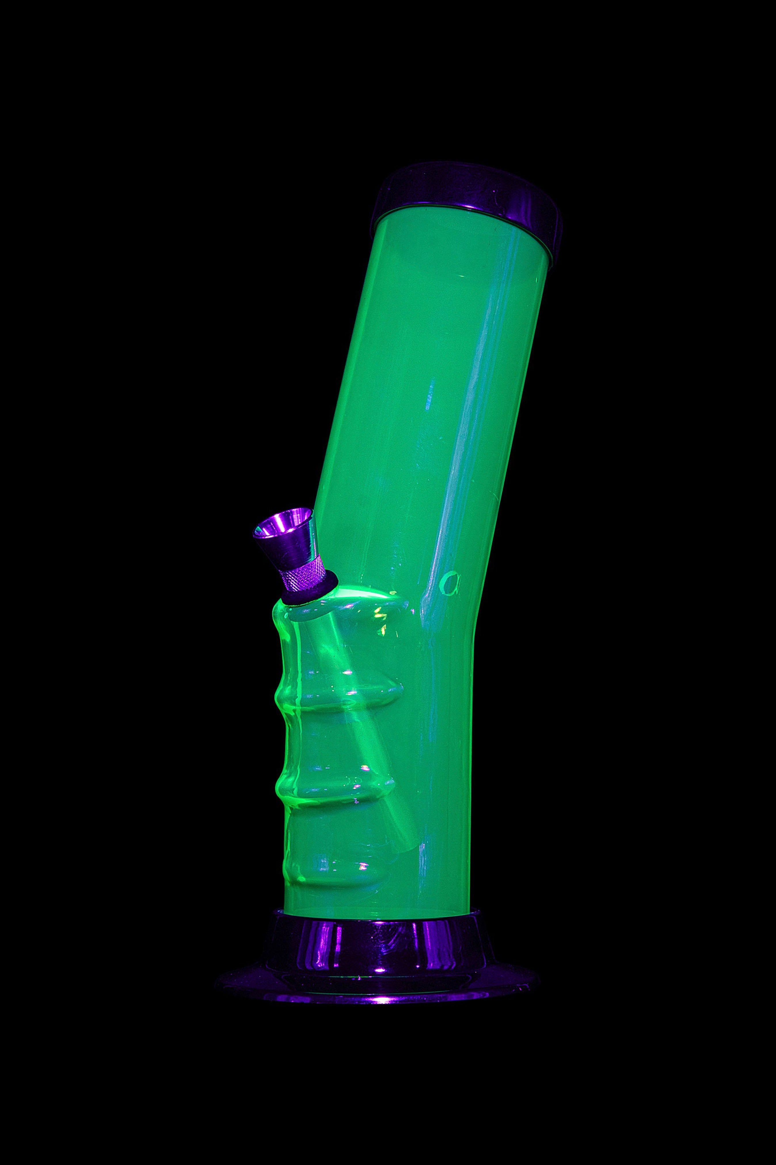 Glowing green glass water pipe against a black background.
