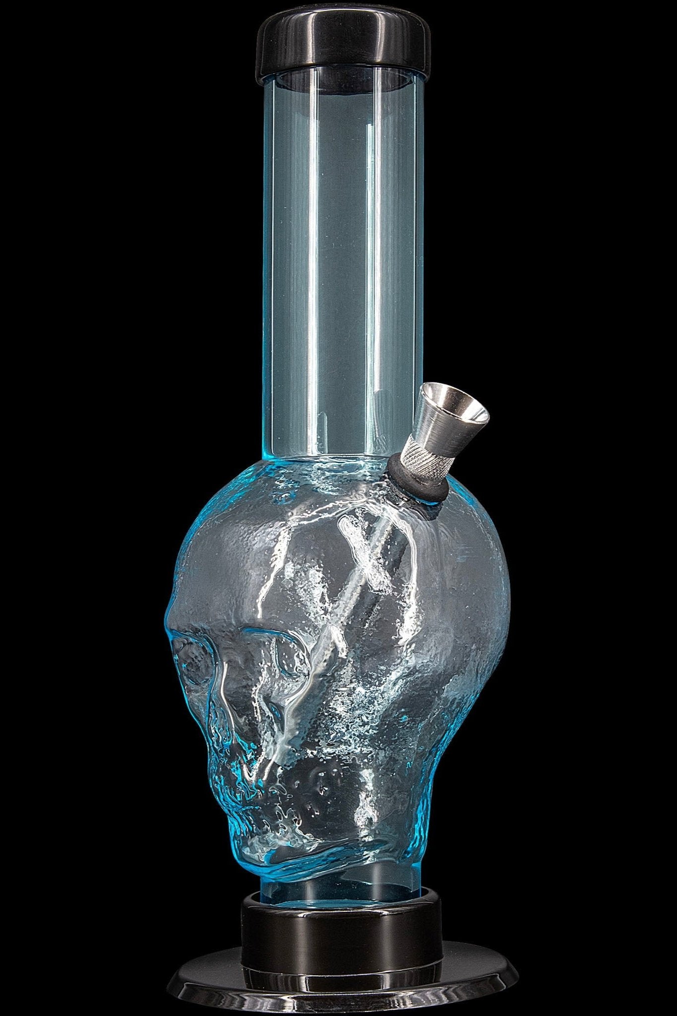 Glass water pipe shaped like a skull, filled with water, against a black background.