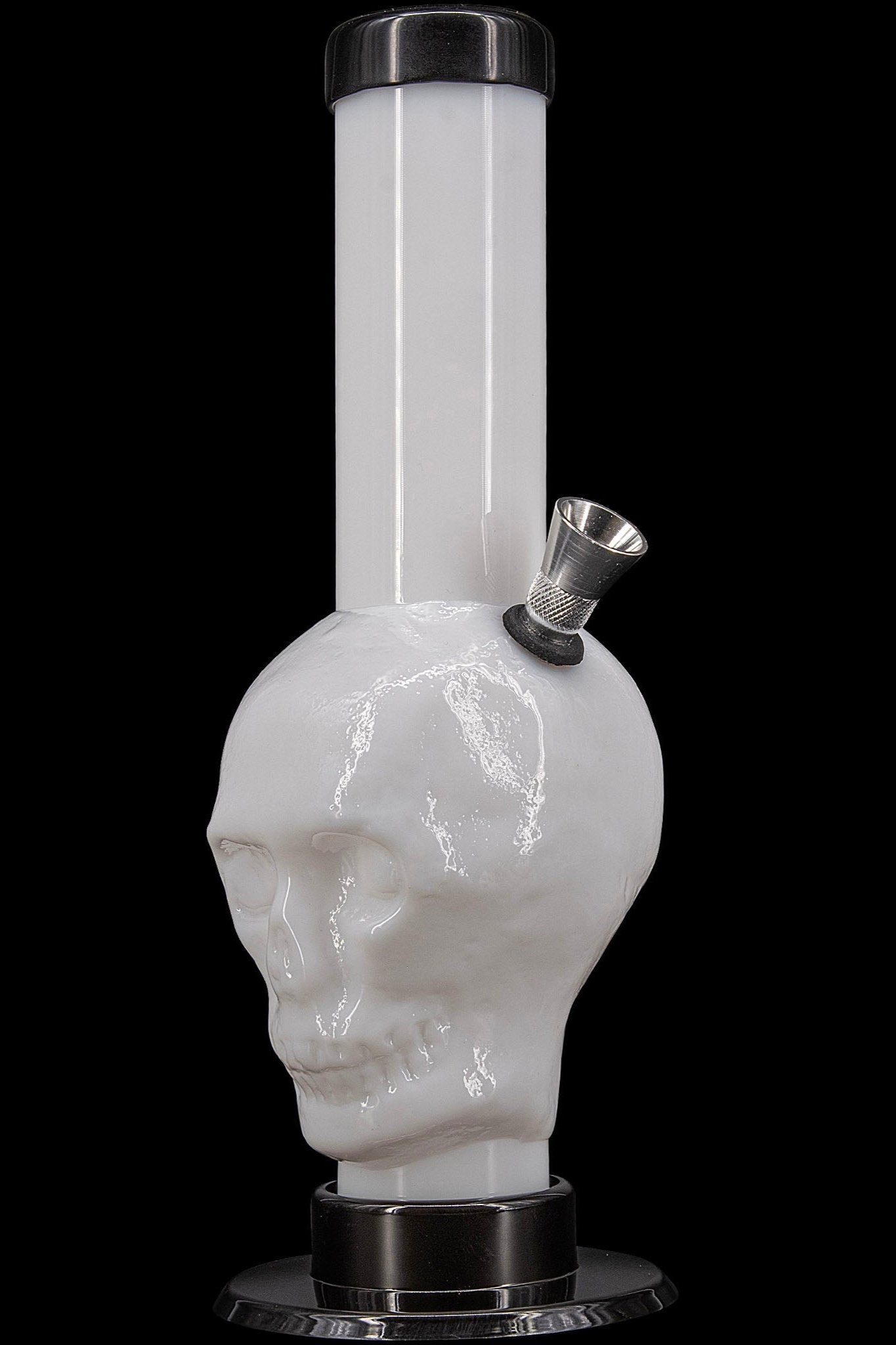 Glass water pipe shaped like a skull with a metal downstem, isolated on black.