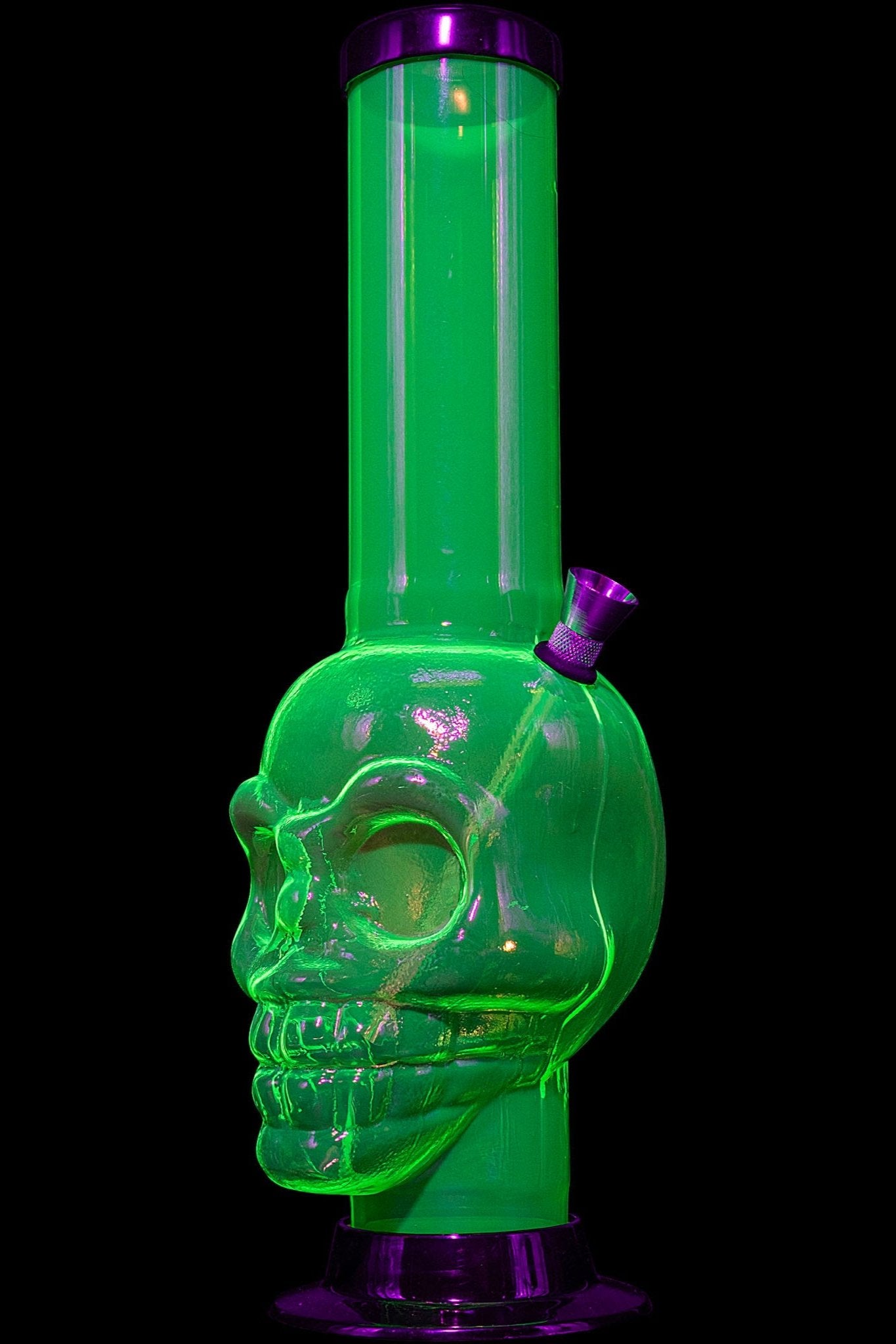 Green glass water pipe shaped like a skull with purple accents, isolated on a black background."