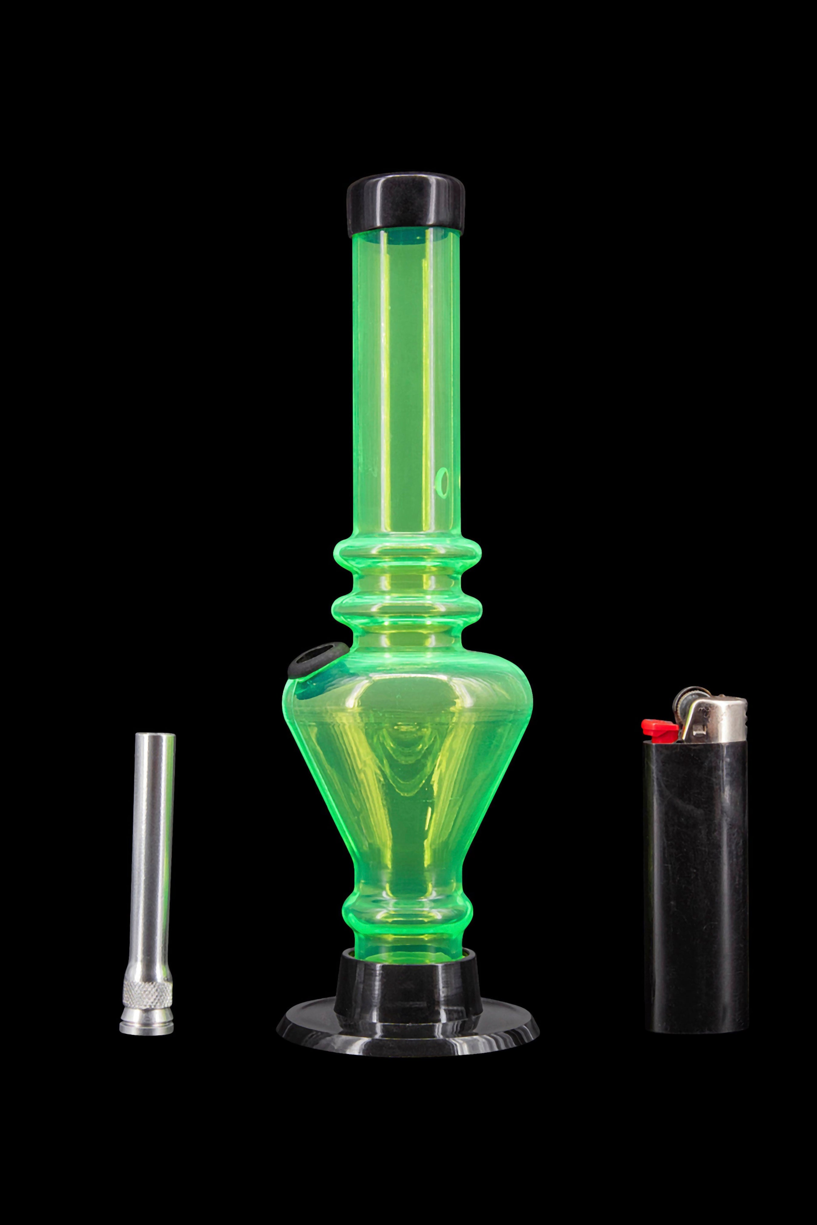 Green glass water pipe (bong) with a metal coil and lighter beside it on a black background.