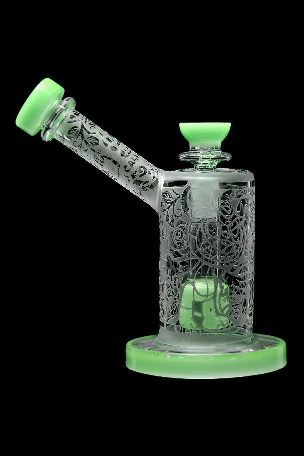 Green glass water pipe with intricate floral carvings, studio shot on black background.