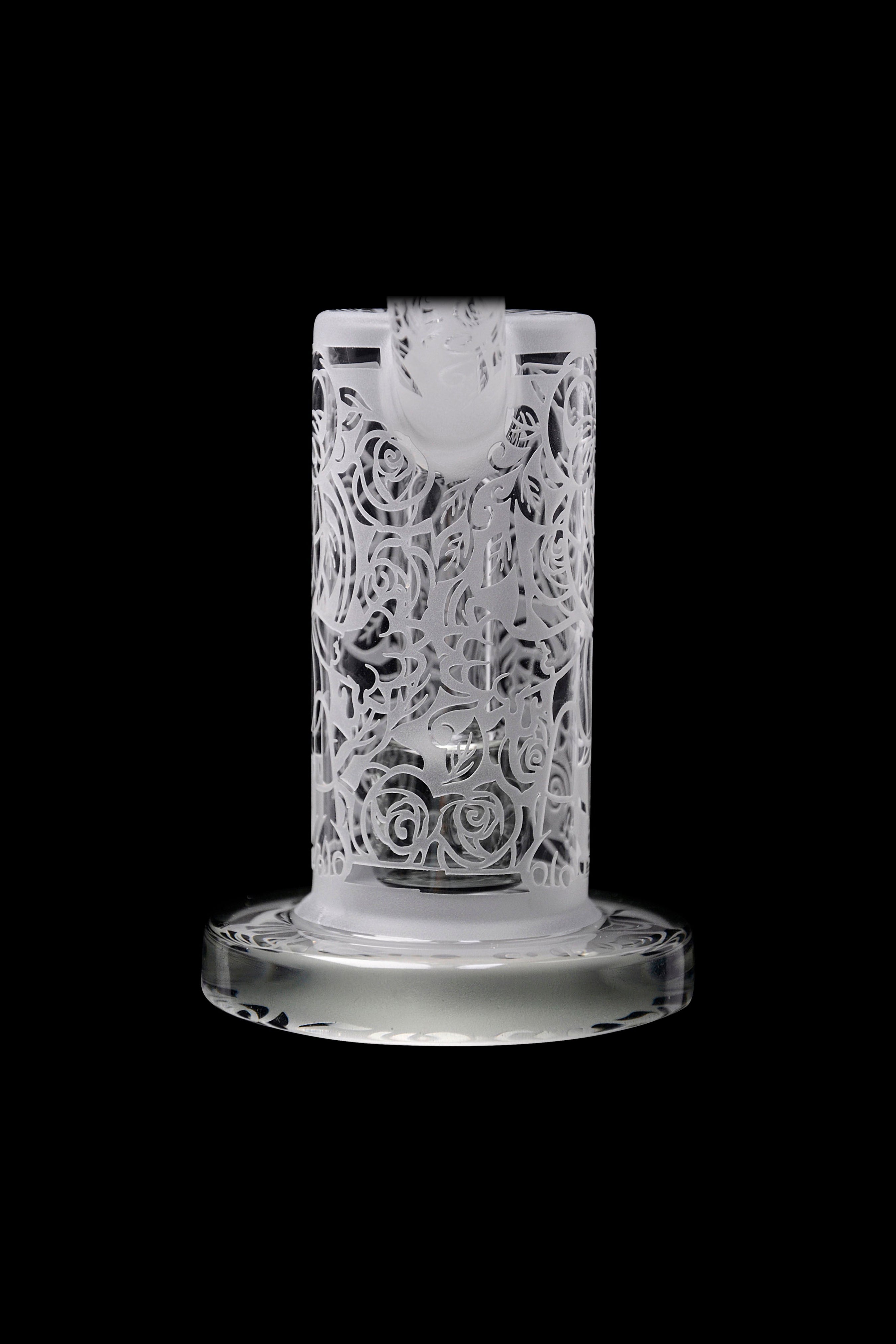 Frosted glass water pipe with intricate rose carvings, isolated on a black background.