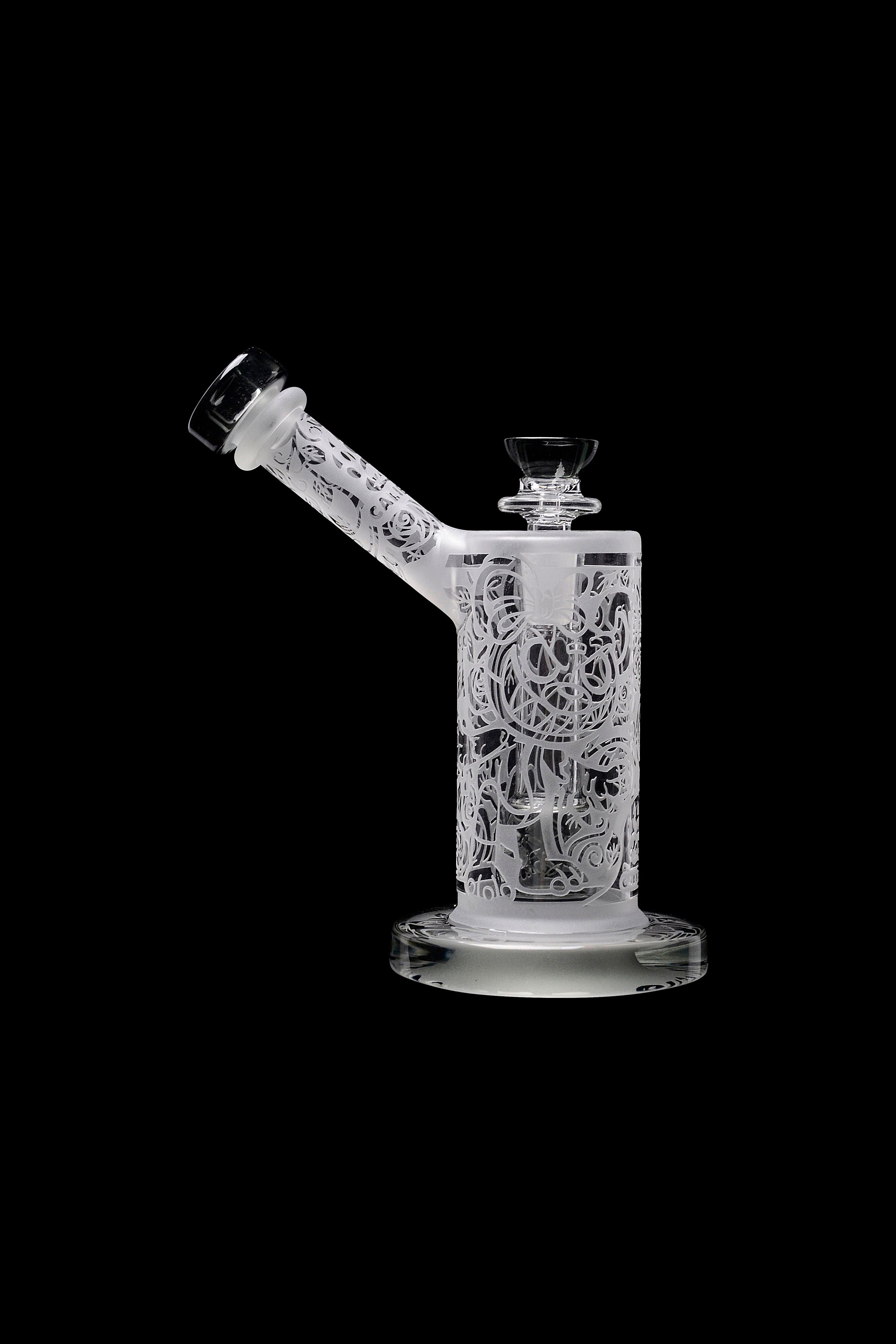 Frosted glass water pipe with intricate floral carvings, isolated on a black background.