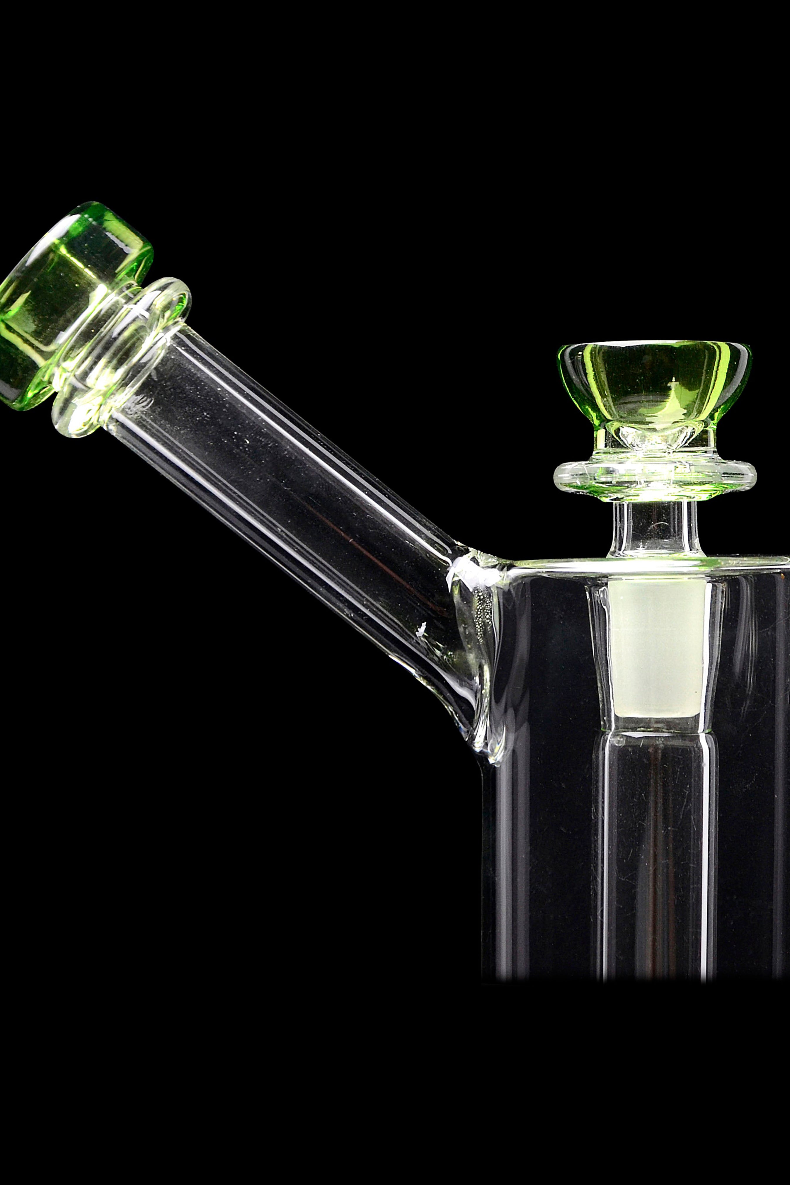 Green and clear glass bubbler/water pipe against a black background.