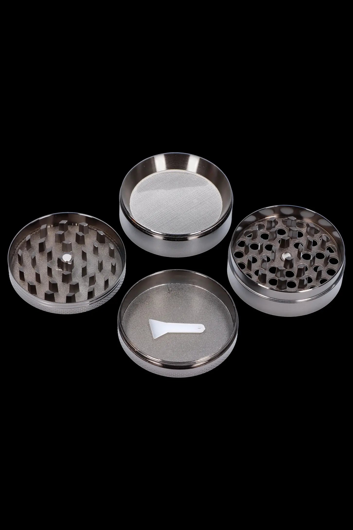 Metal cannabis grinder disassembled into its component parts on a black background.