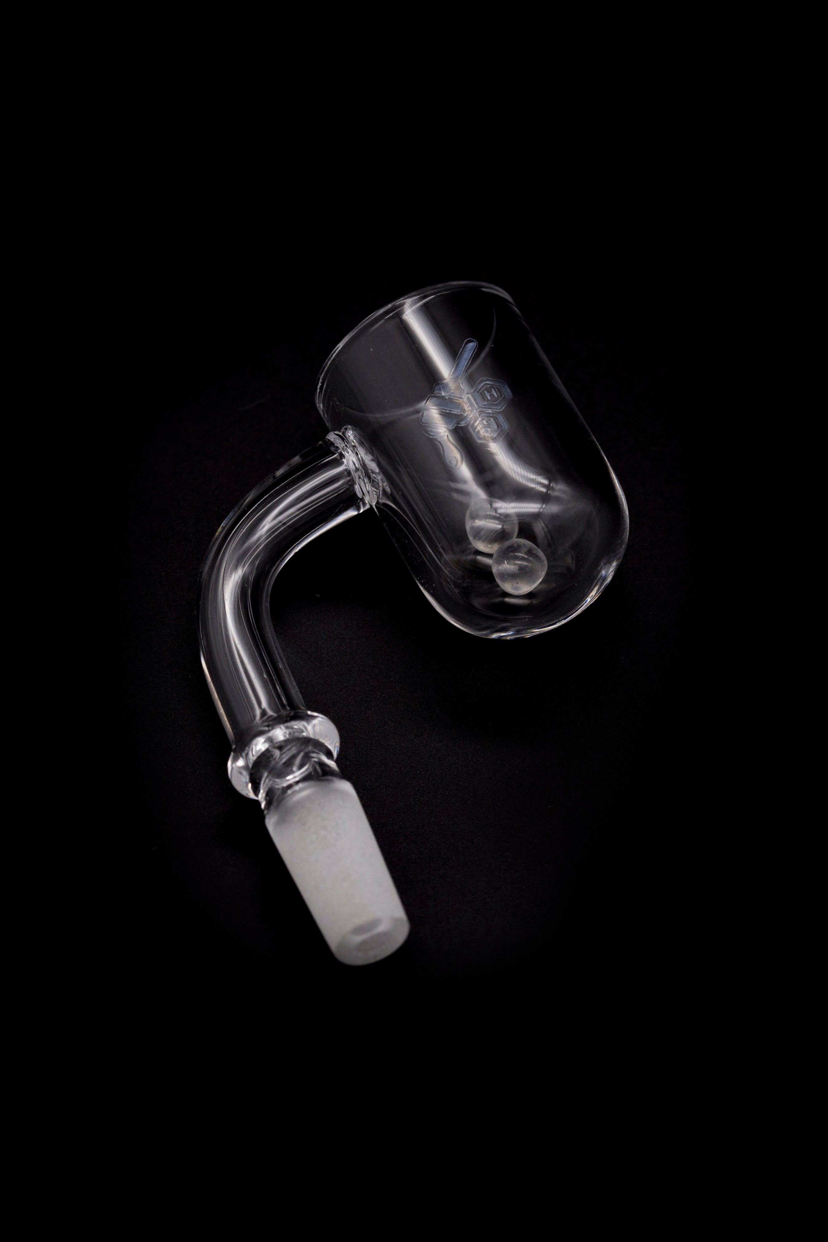 Clear glass dab rig nail with etched design against a black background.