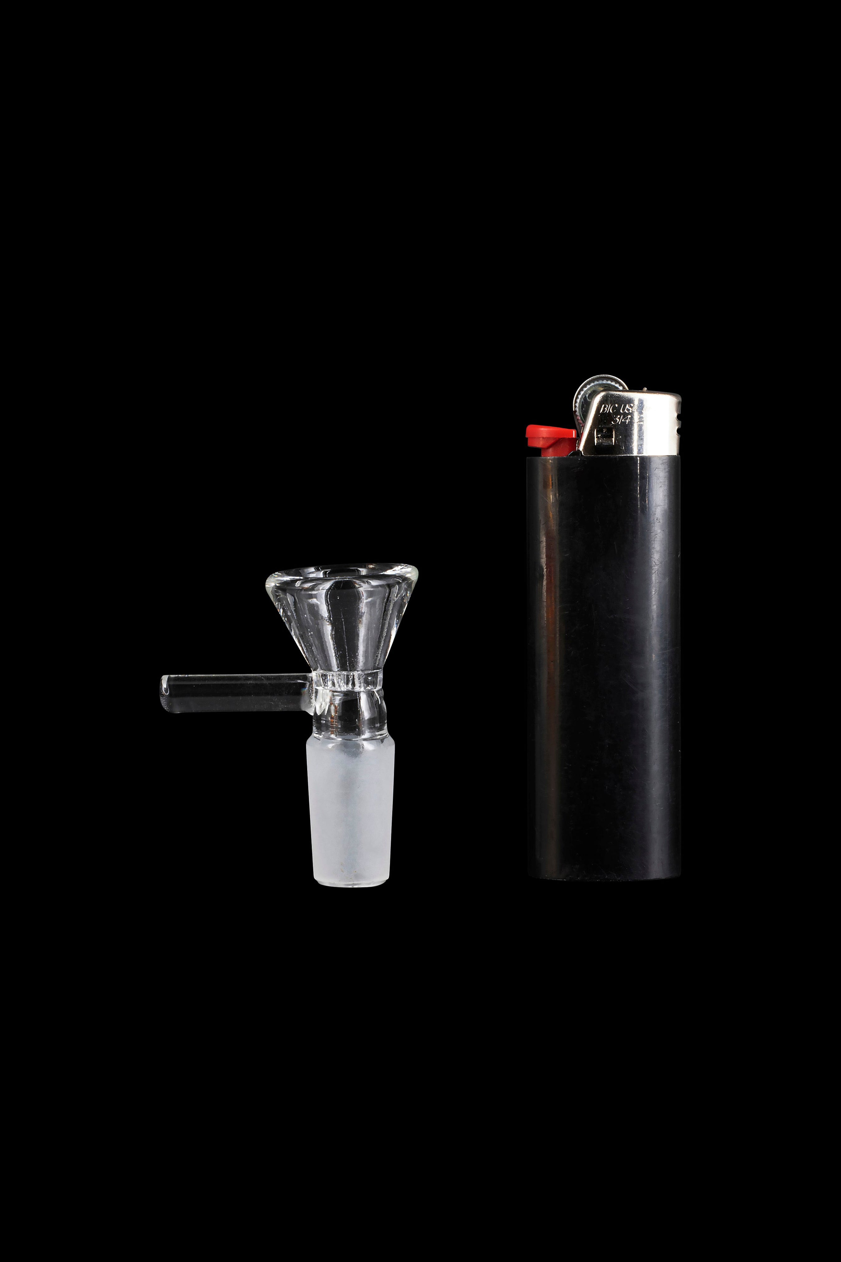 Glass bowl and black lighter on a black background.