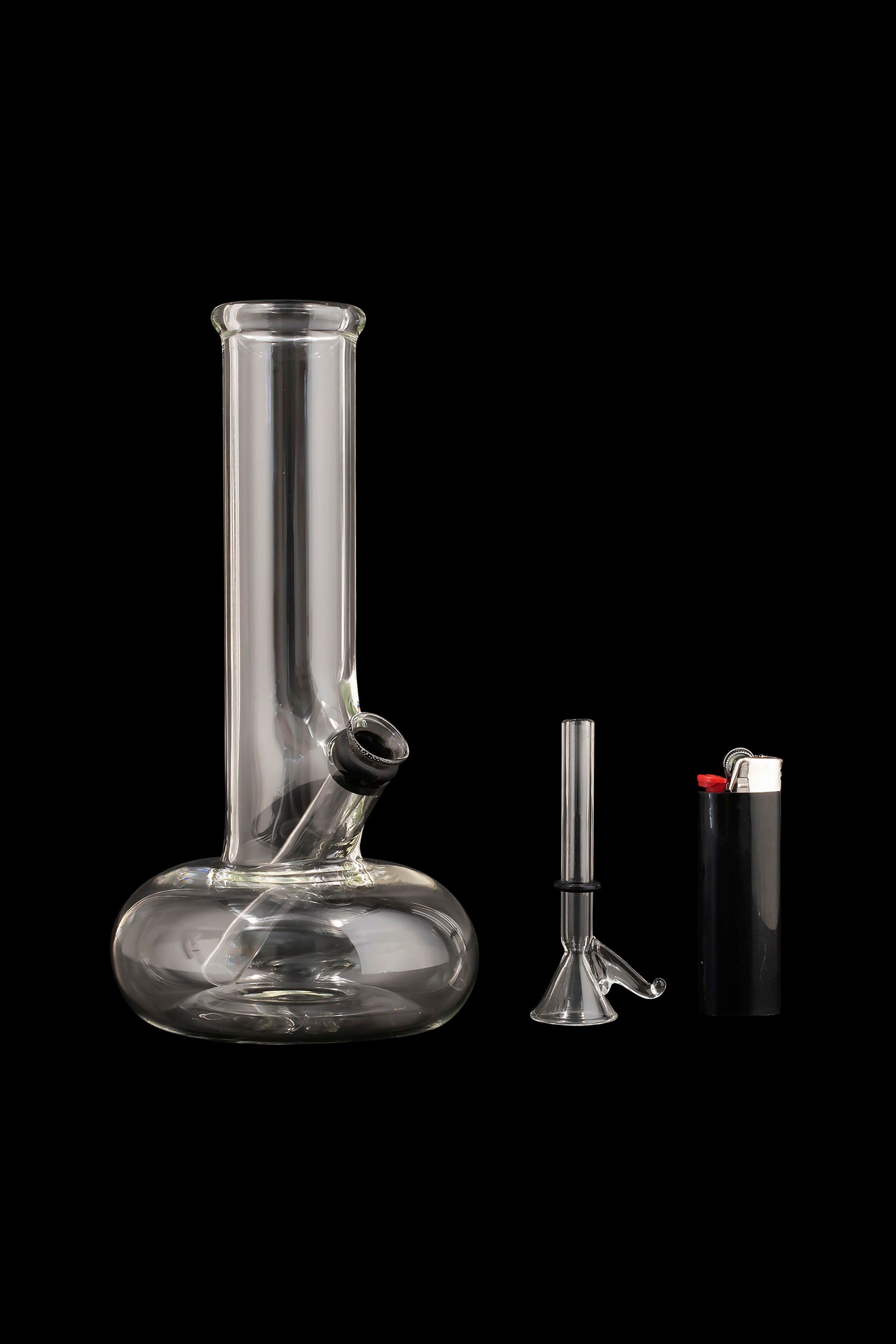 Glass bong, downstem, and lighter on a black background.