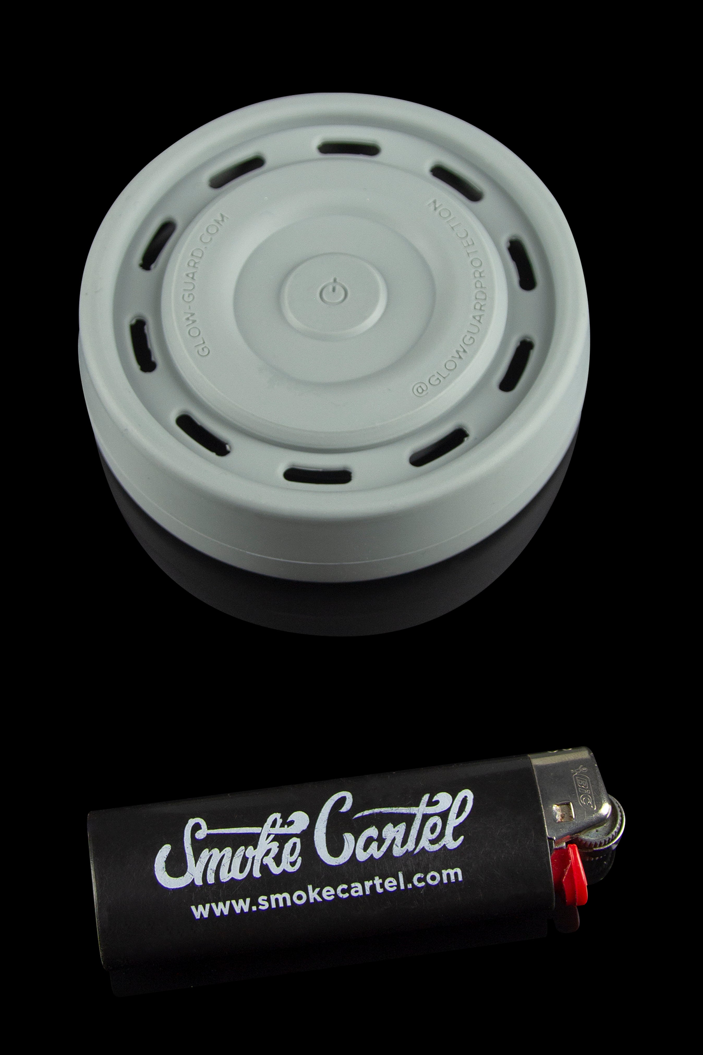 A grey silicone carb cap rests above a black lighter with "Smoke Cartel" branding and website address.