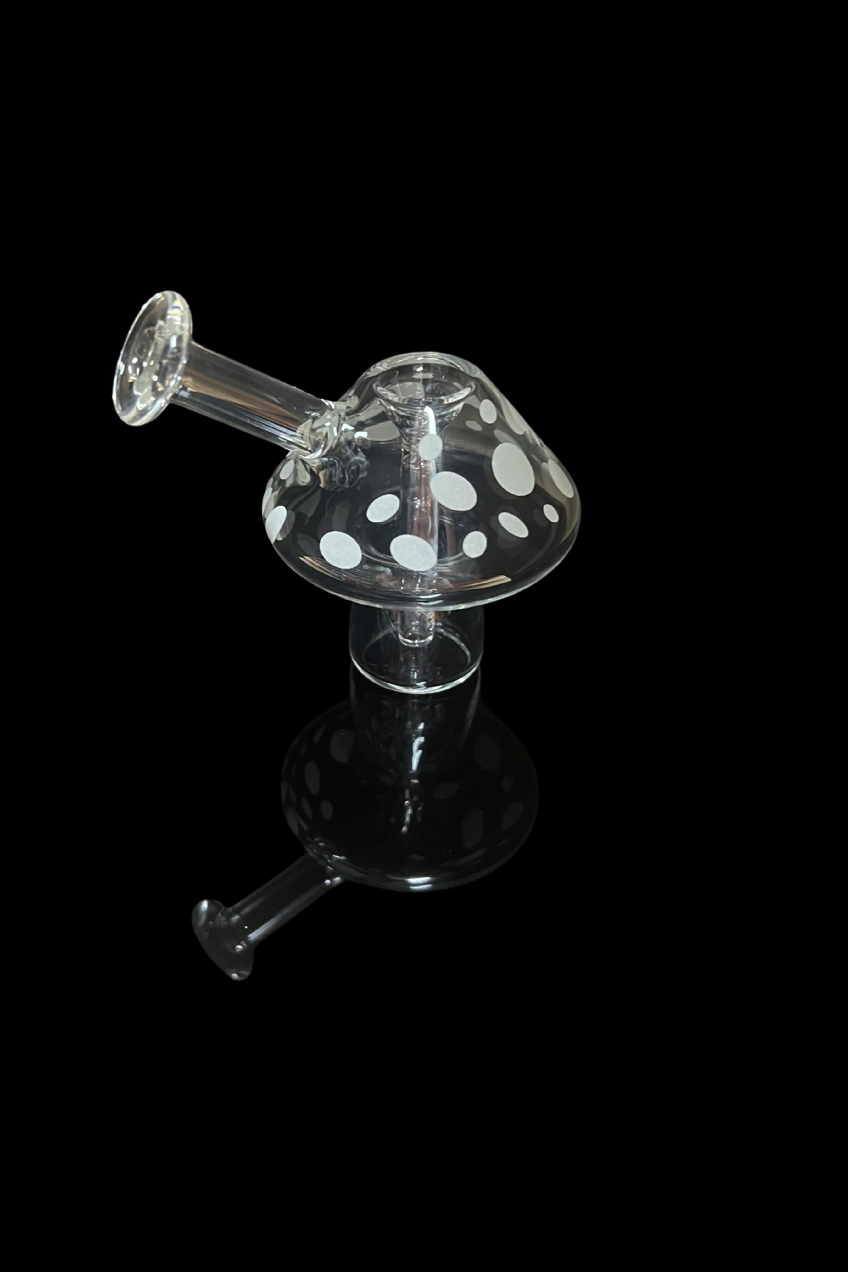 Clear glass mushroom-shaped oil rig with speckled cap, isolated on black.