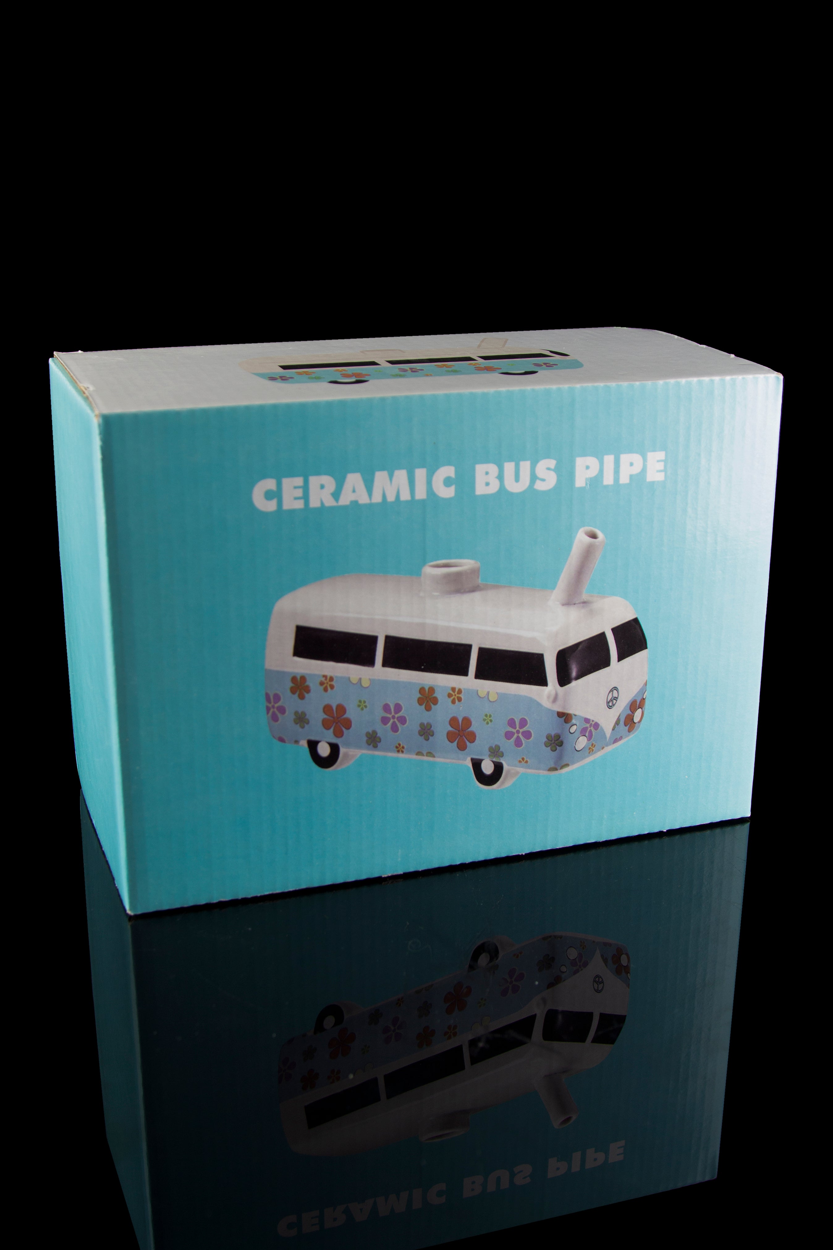 Colorful turquoise box displaying a ceramic Volkswagen-style bus pipe with floral details, reflected on a glossy surface.