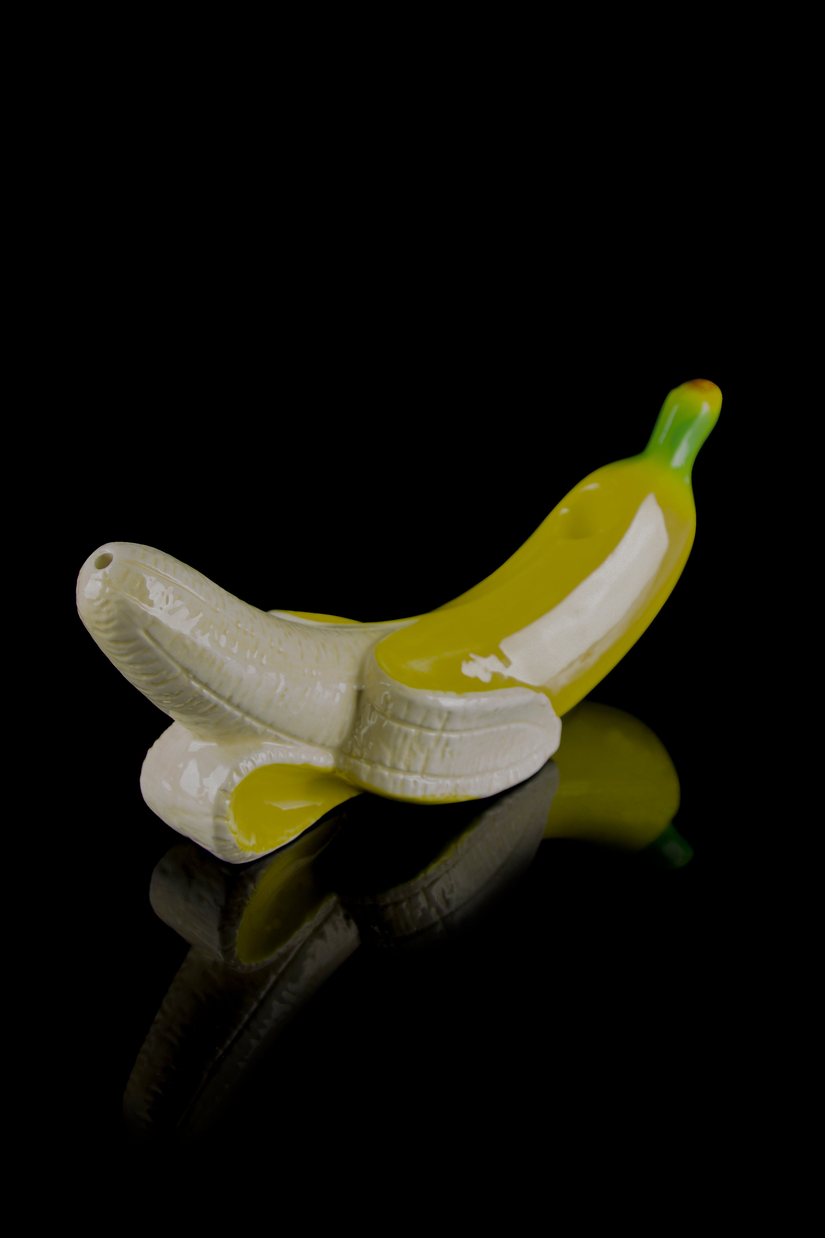 Glass banana-shaped smoking piece with a reflective surface, isolated on black.