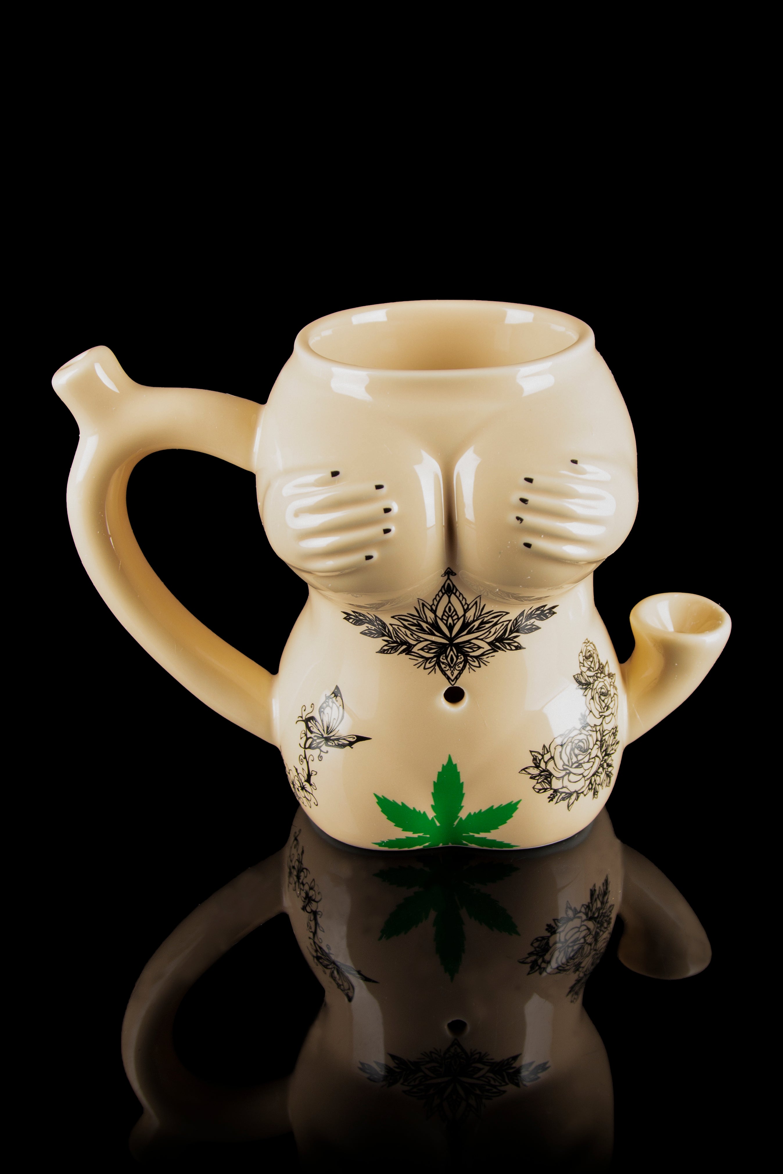 Ceramic water pipe shaped like a torso with botanical tattoos and a cannabis leaf detail, reflected on a glossy surface.