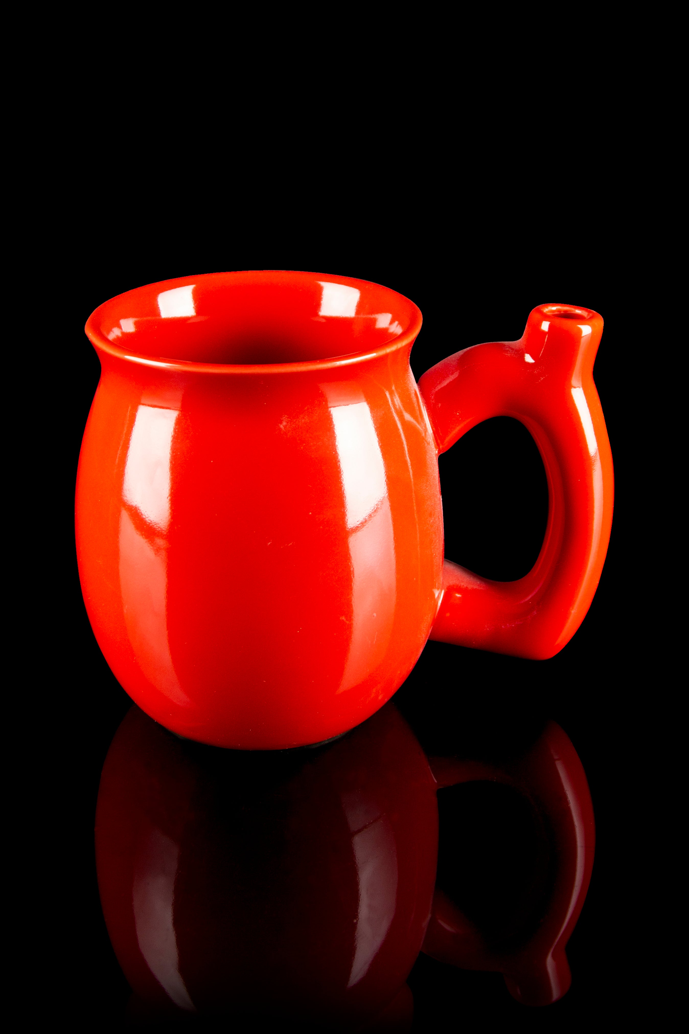Red ceramic cannabis water pipe with a rounded base and looped handle, reflected on a black surface.