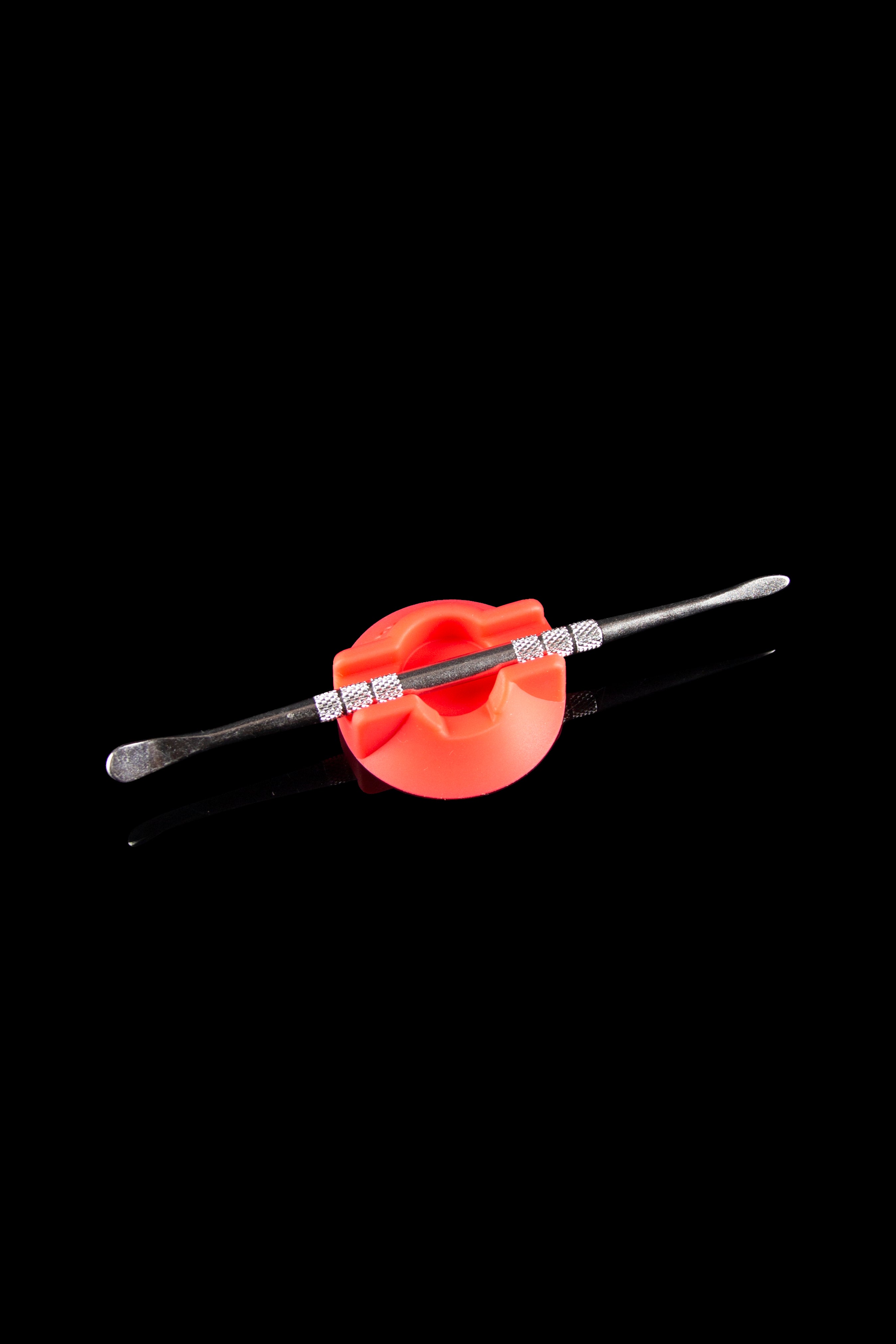 Silver dab tool with a red silicone holder, isolated on a black background.