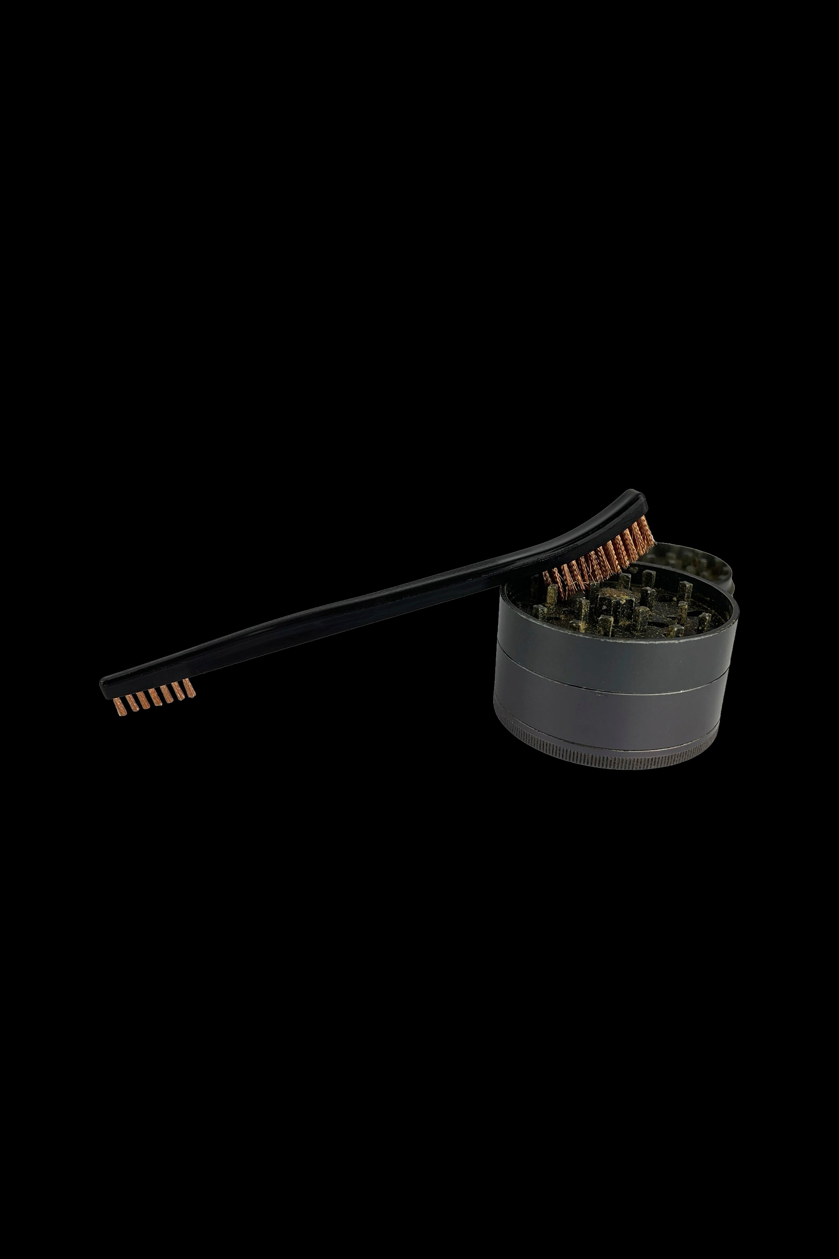 Black metal cannabis grinder with cleaning brush.