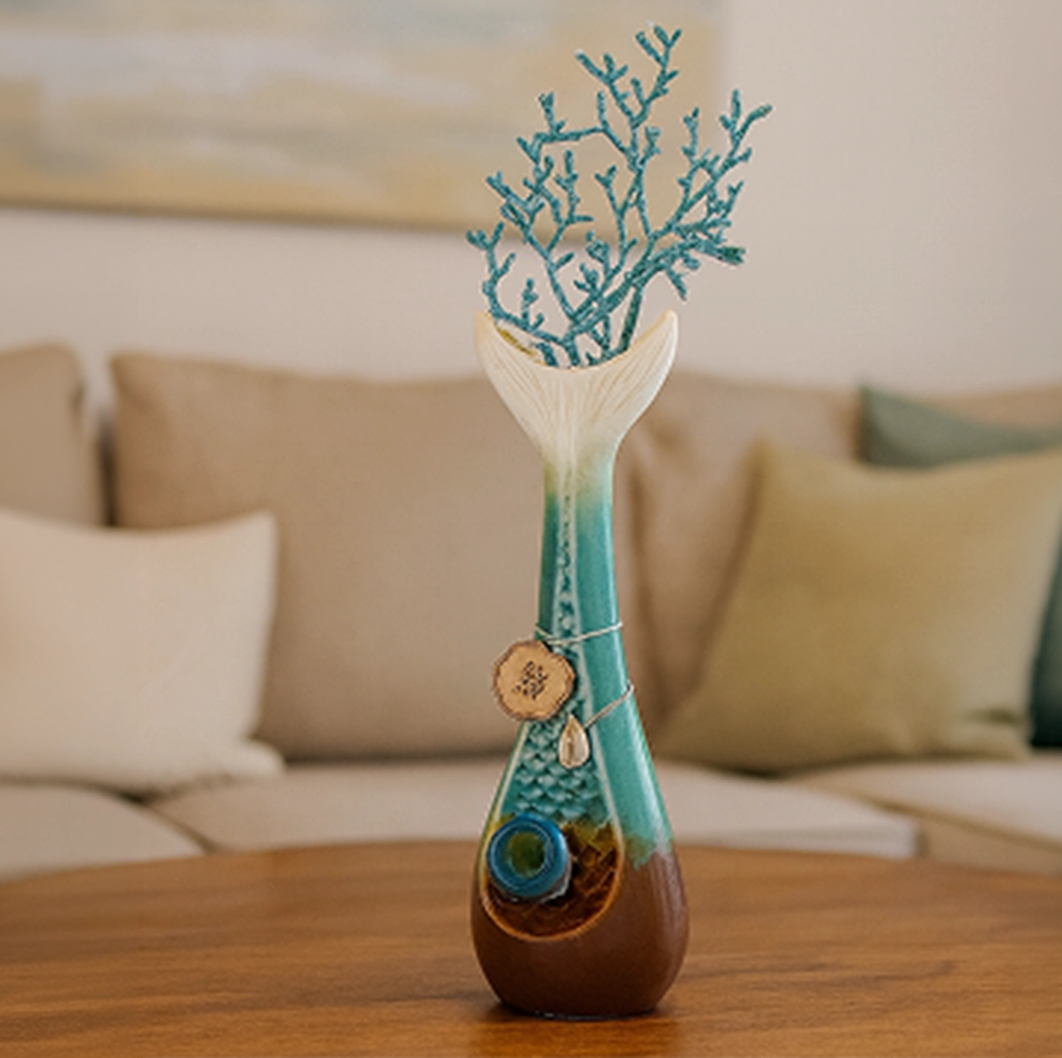 Center-frontal view of the My Bud Vase "Mermaid" Bong standing on a wooden table with teal coral stems and soft couch background