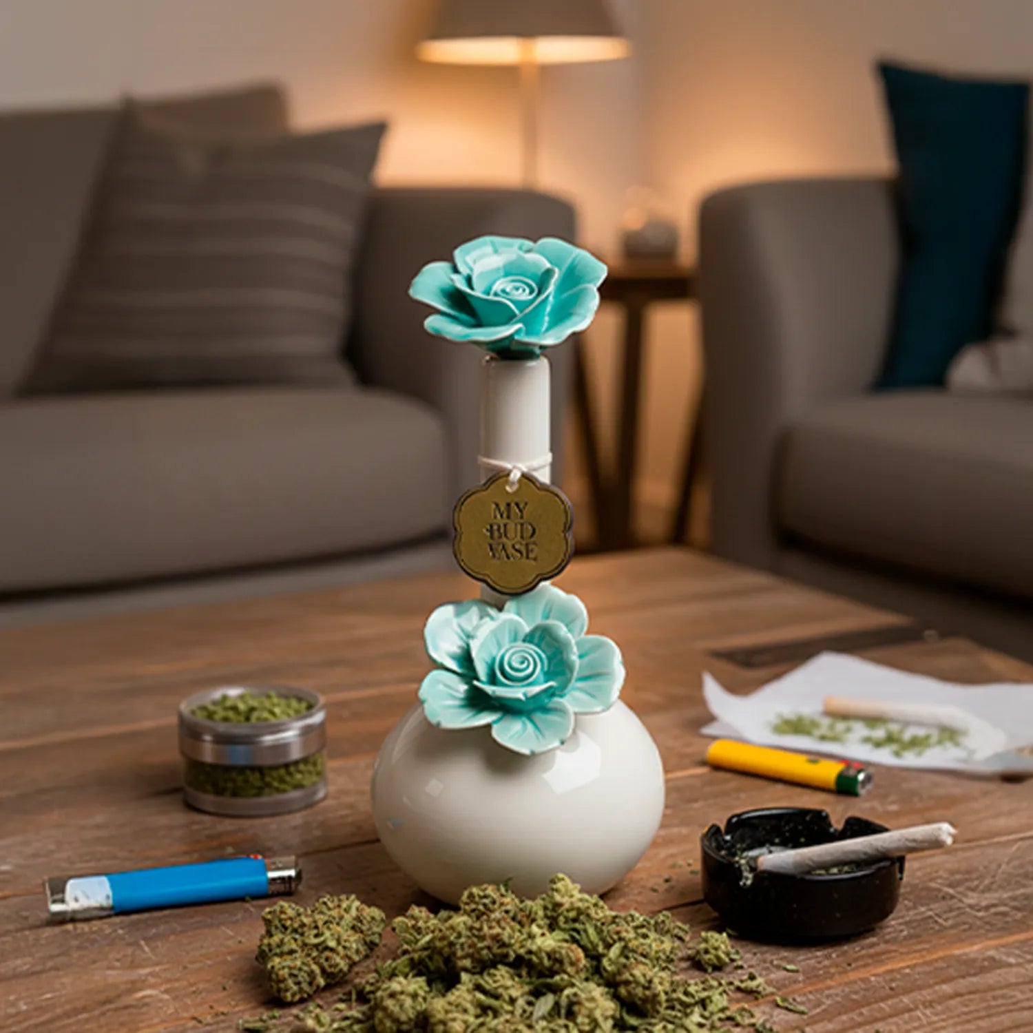 Center-framed close-up of the My Bud Vase Bong - Rosette showing a white round base and two teal ceramic rosette flowers on a wooden table.
