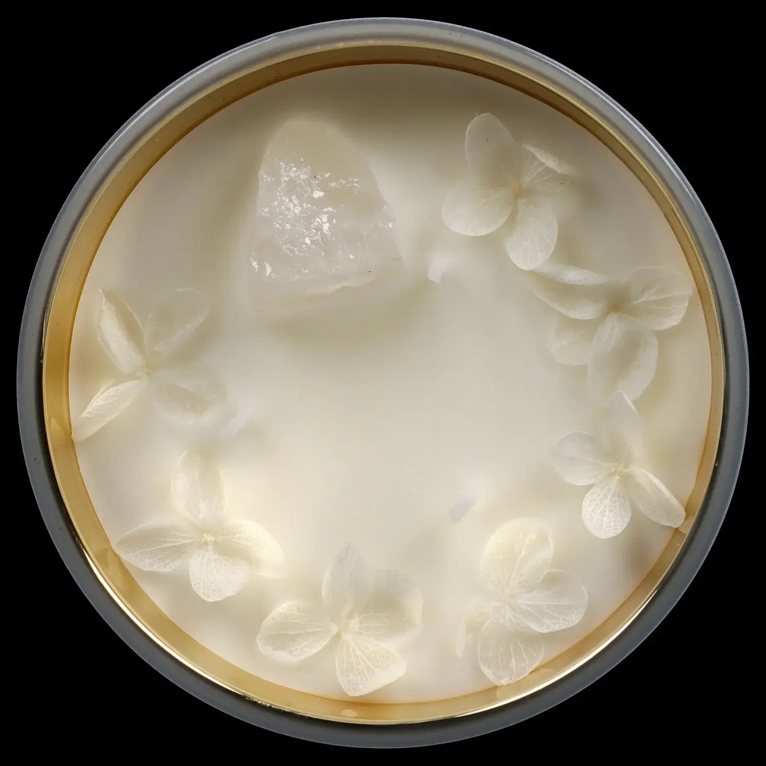 Close-up of a clear glass jar filled with white, creamy cannabis concentrate, encircled by small, translucent cannabis buds.