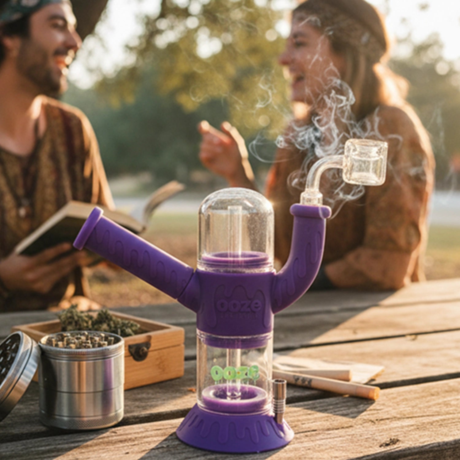 Low-angle view of an Ooze "Cranium" Silicone 4-in-1 Glass Bong in purple with smoke curling from its glass mouthpiece on a picnic table