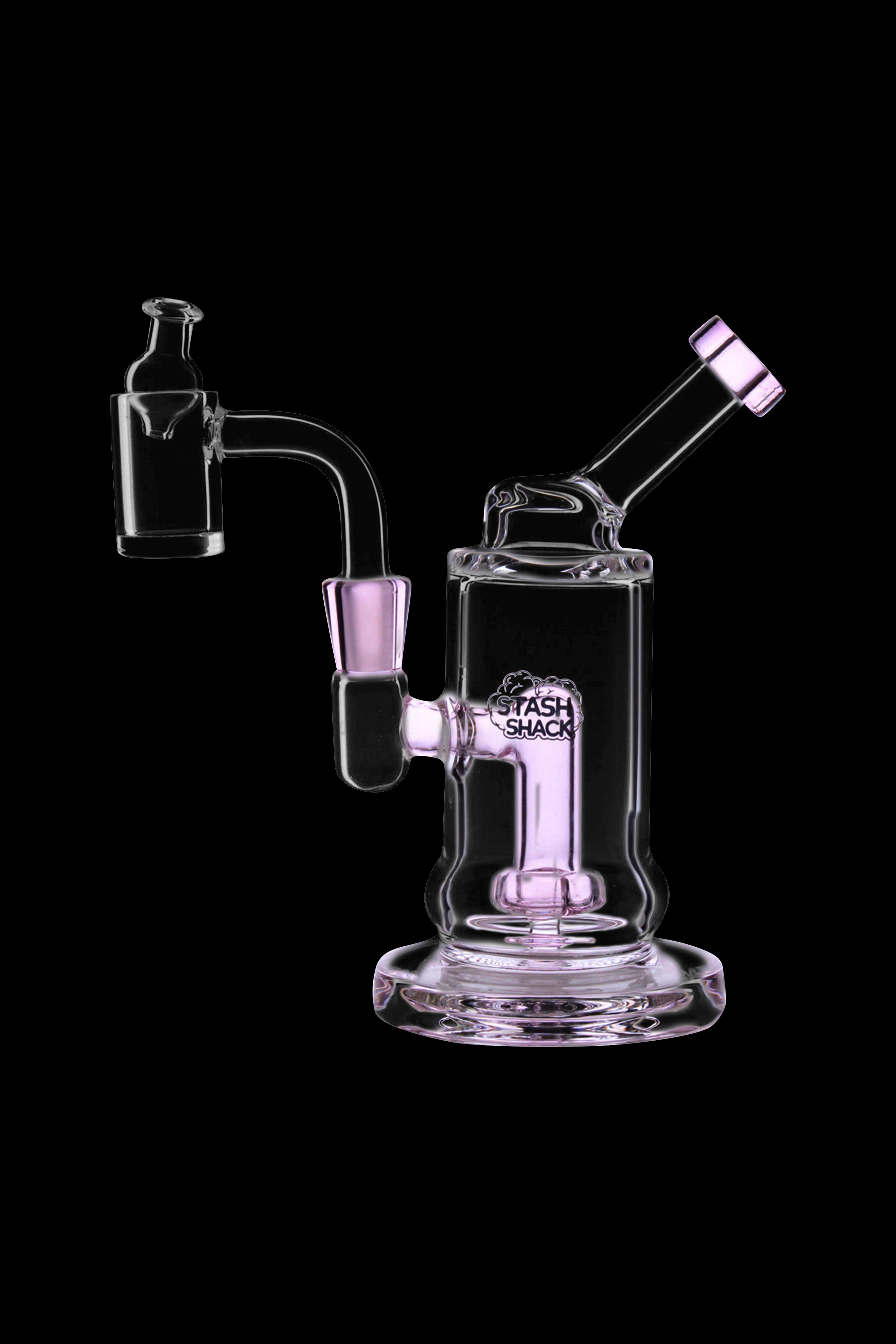 Pink glass dab rig with a quartz banger and accessories, isolated on a black background.