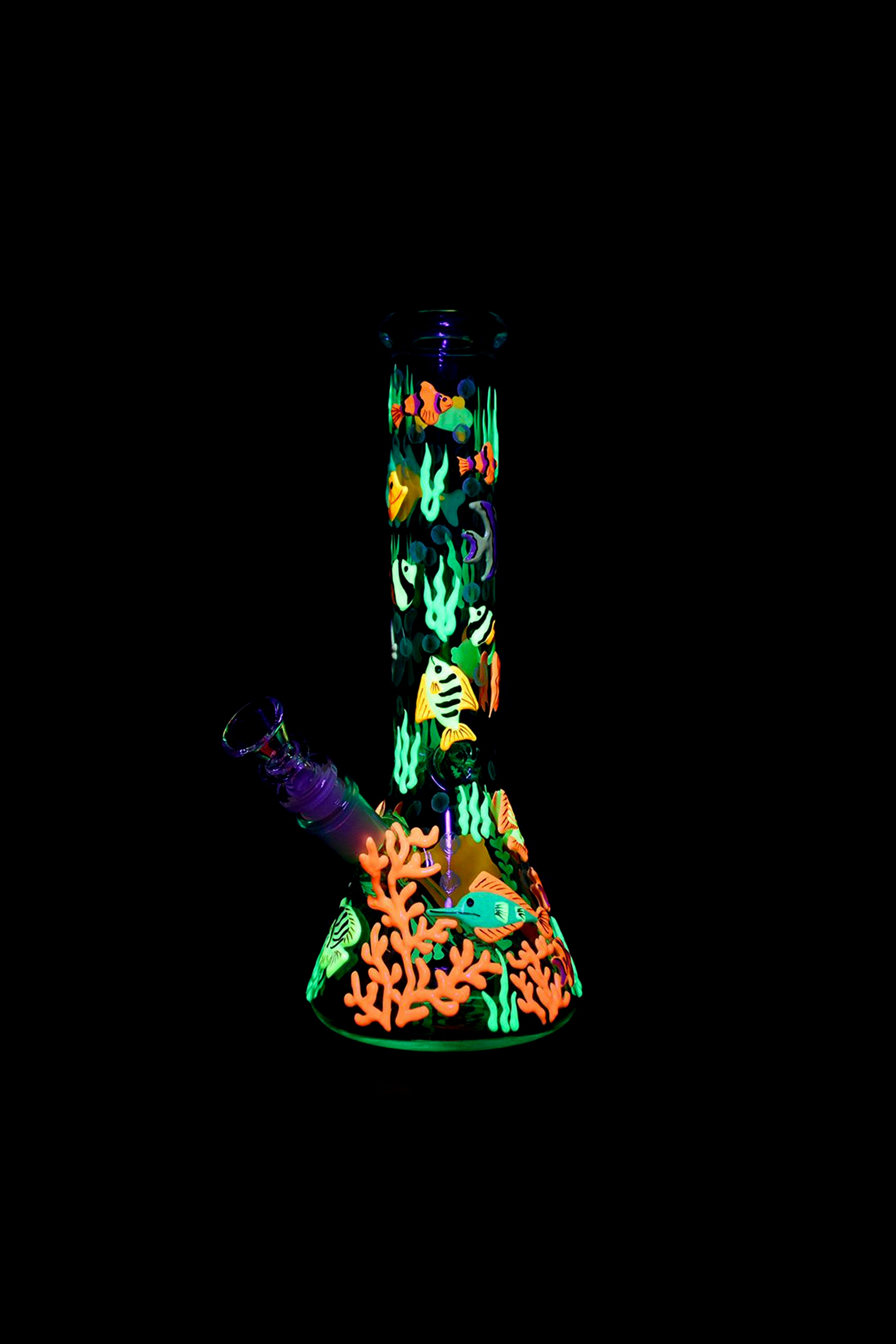 Glowing glass water pipe decorated with vibrant coral reef and fish designs against a black background.