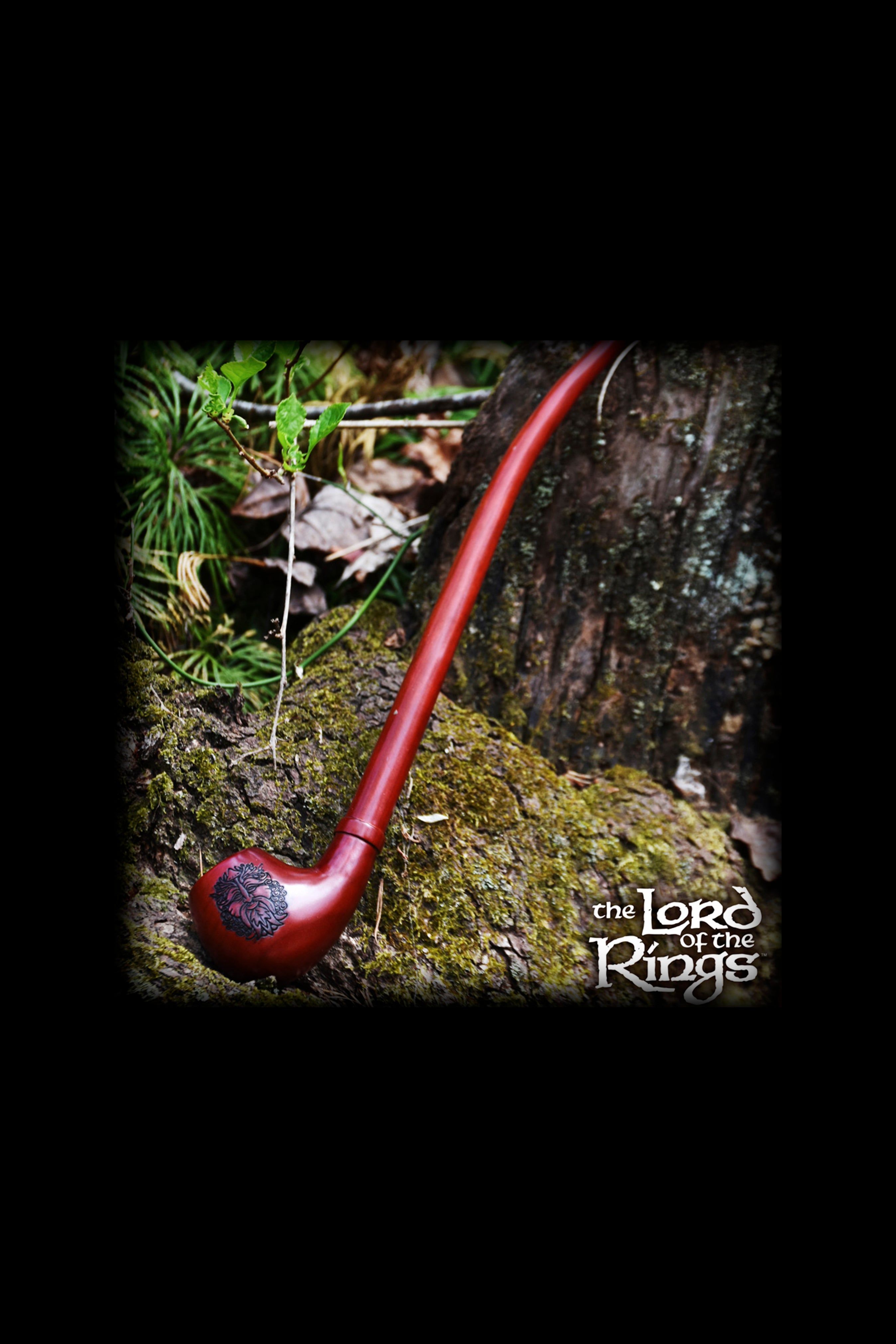 A long, curved, reddish-brown smoking pipe rests on a mossy surface, evoking imagery from *The Lord of the Rings*.