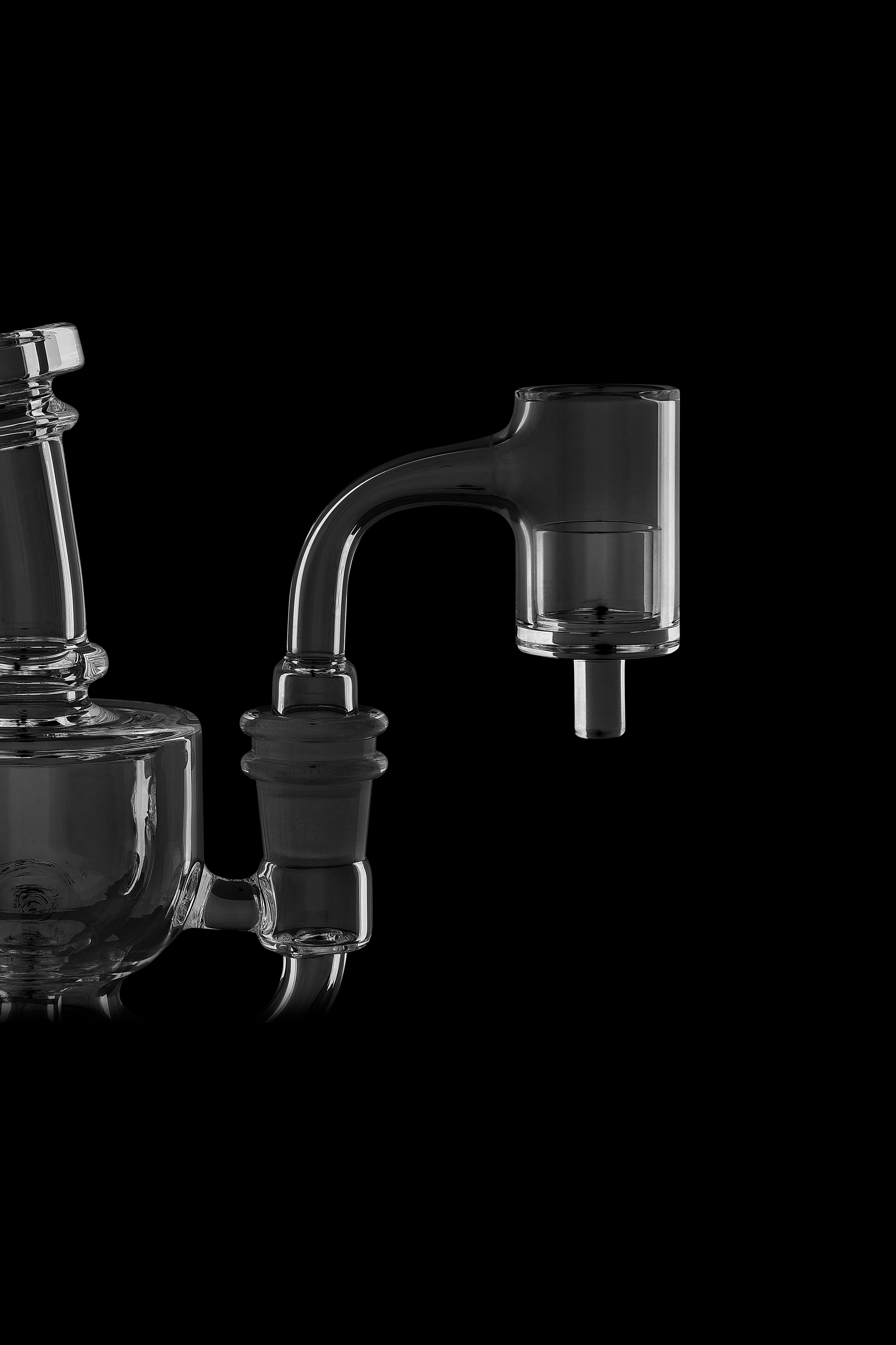 Clear glass dab rig with accessories against a black background.